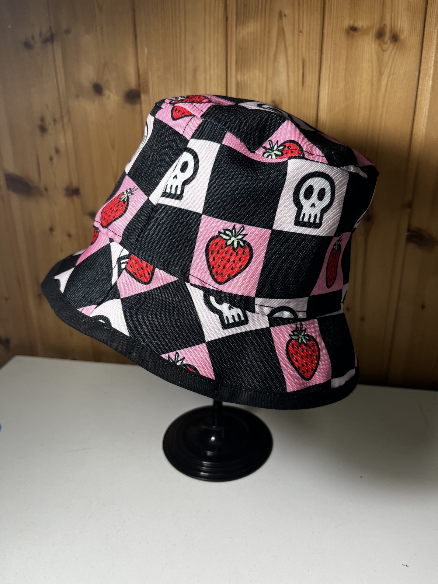 Chapéu de balde com padrão xadrez preto e rosa com morangos e caveiras