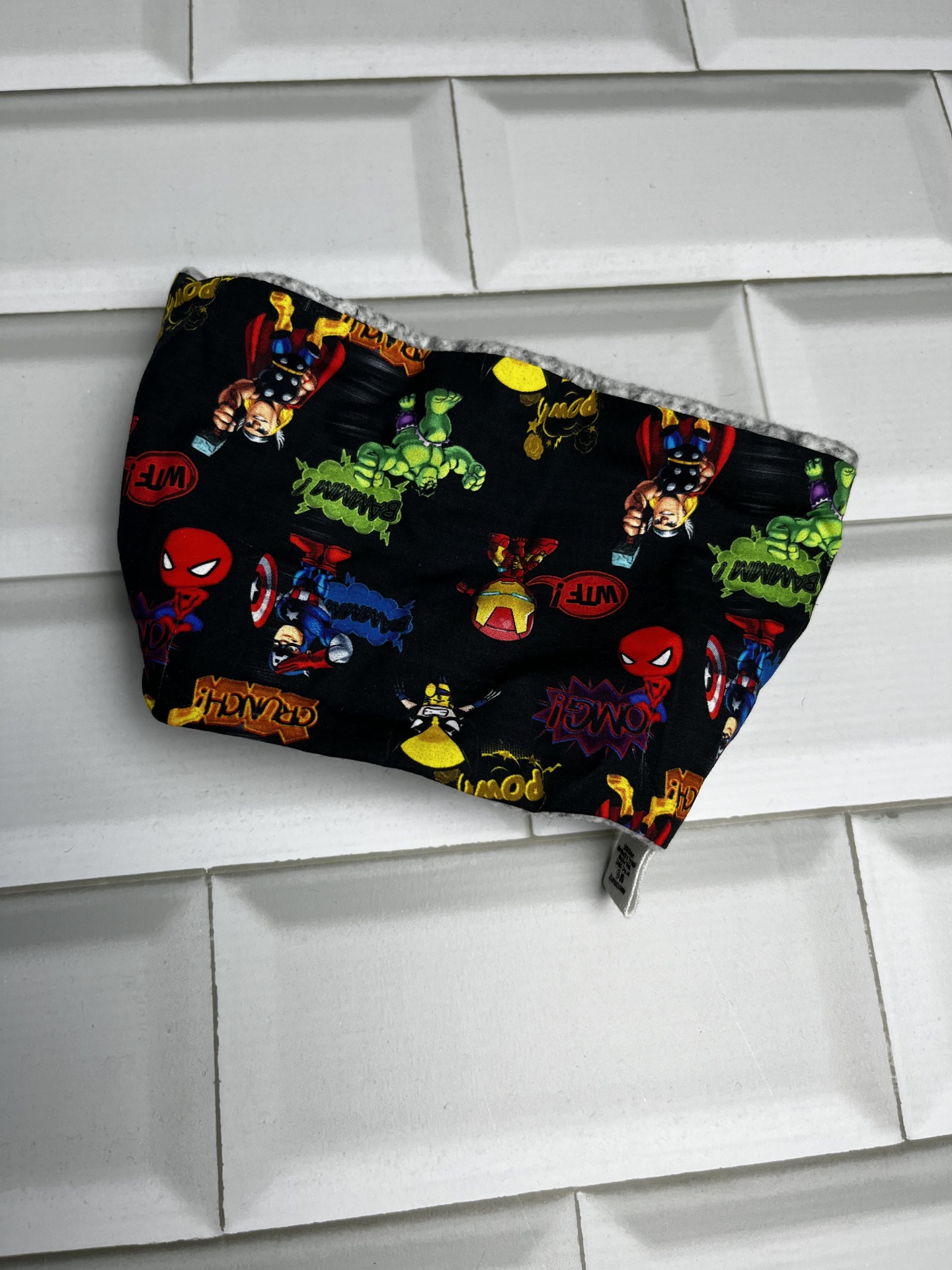 Máscara facial preta com personagens de super-heróis coloridos