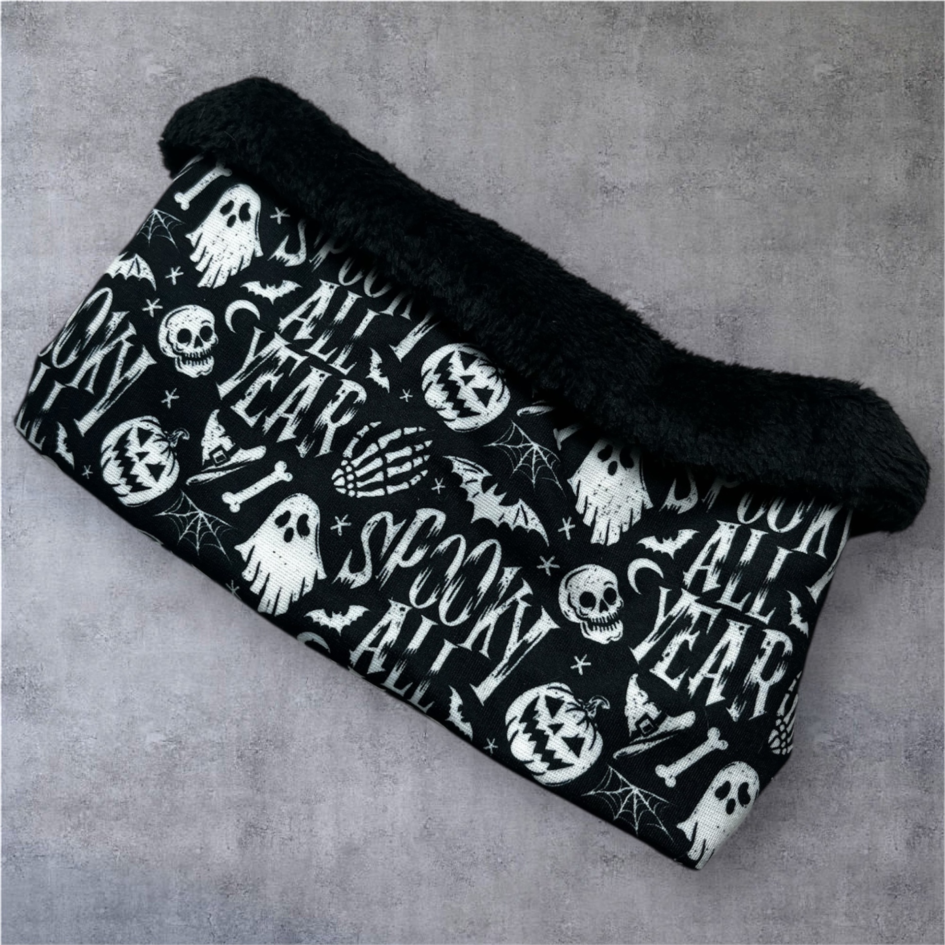 Cachecol tubular preto com desenhos Halloween brancos e faixa peluda preta.