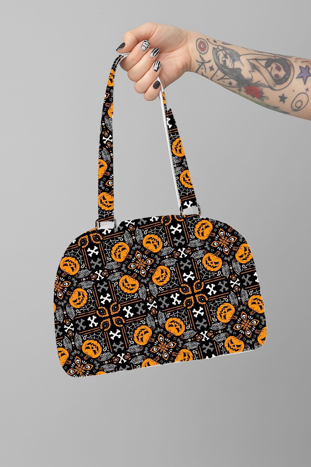 Mala com padrão de Halloween segurada por uma mão tatuada