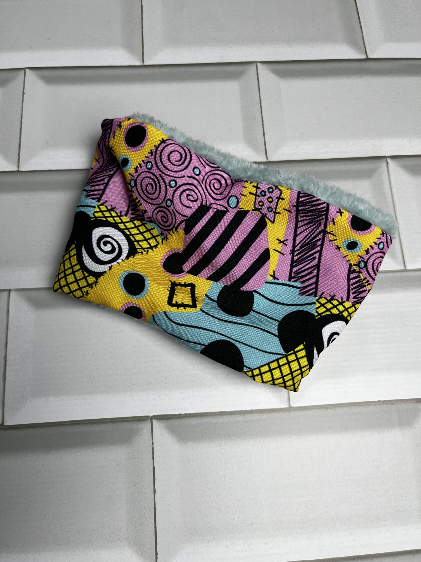 Cachecol tubular colorido com padrão geométrico e espirais em fundo branco