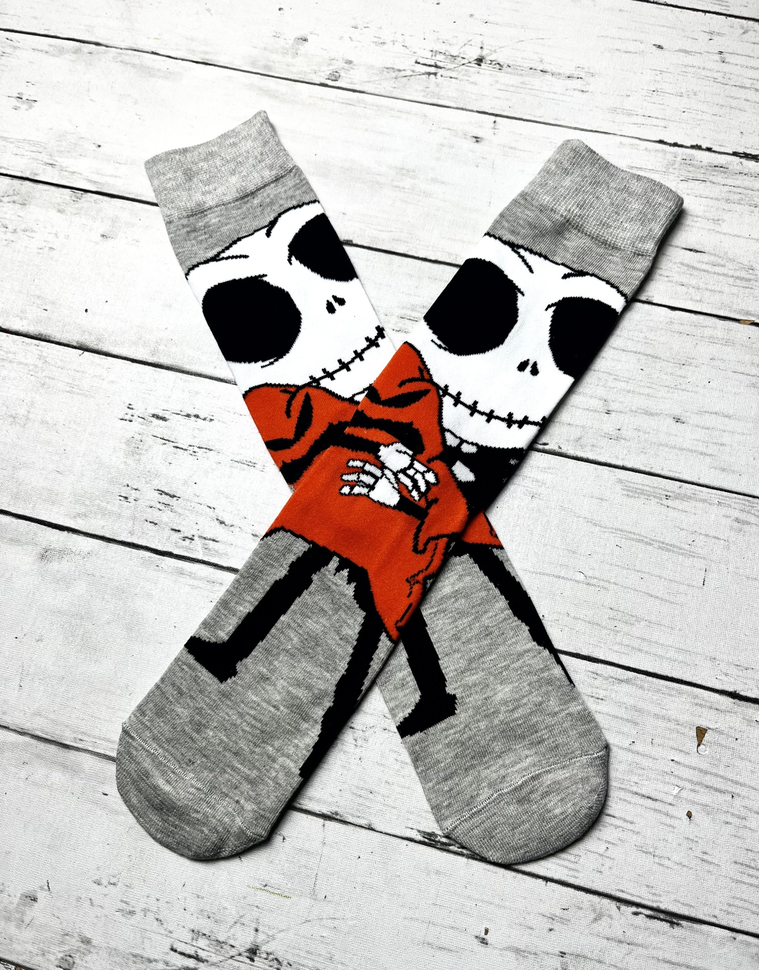 Meias cinzentas com esqueleto estampado com casaco vermelho sobre fundo de madeira