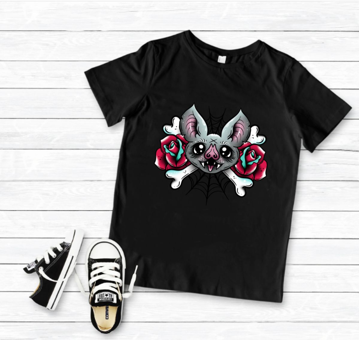 T-shirt preta com estampa de morcego entre rosas e ossos, com ténis pretos e brancos ao lado