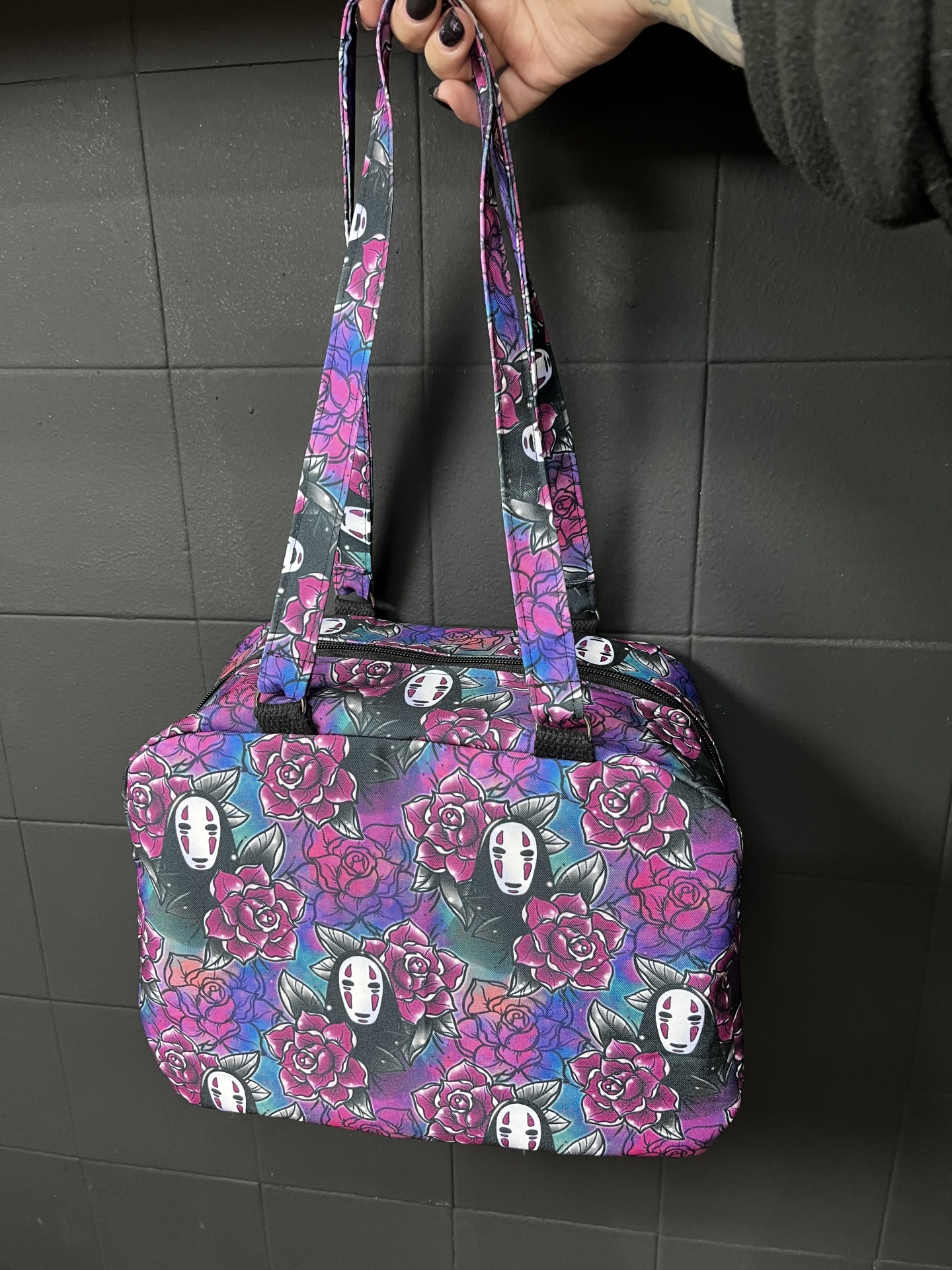 Mala quadrada colorida com padrão de rosas e rostos estilizados