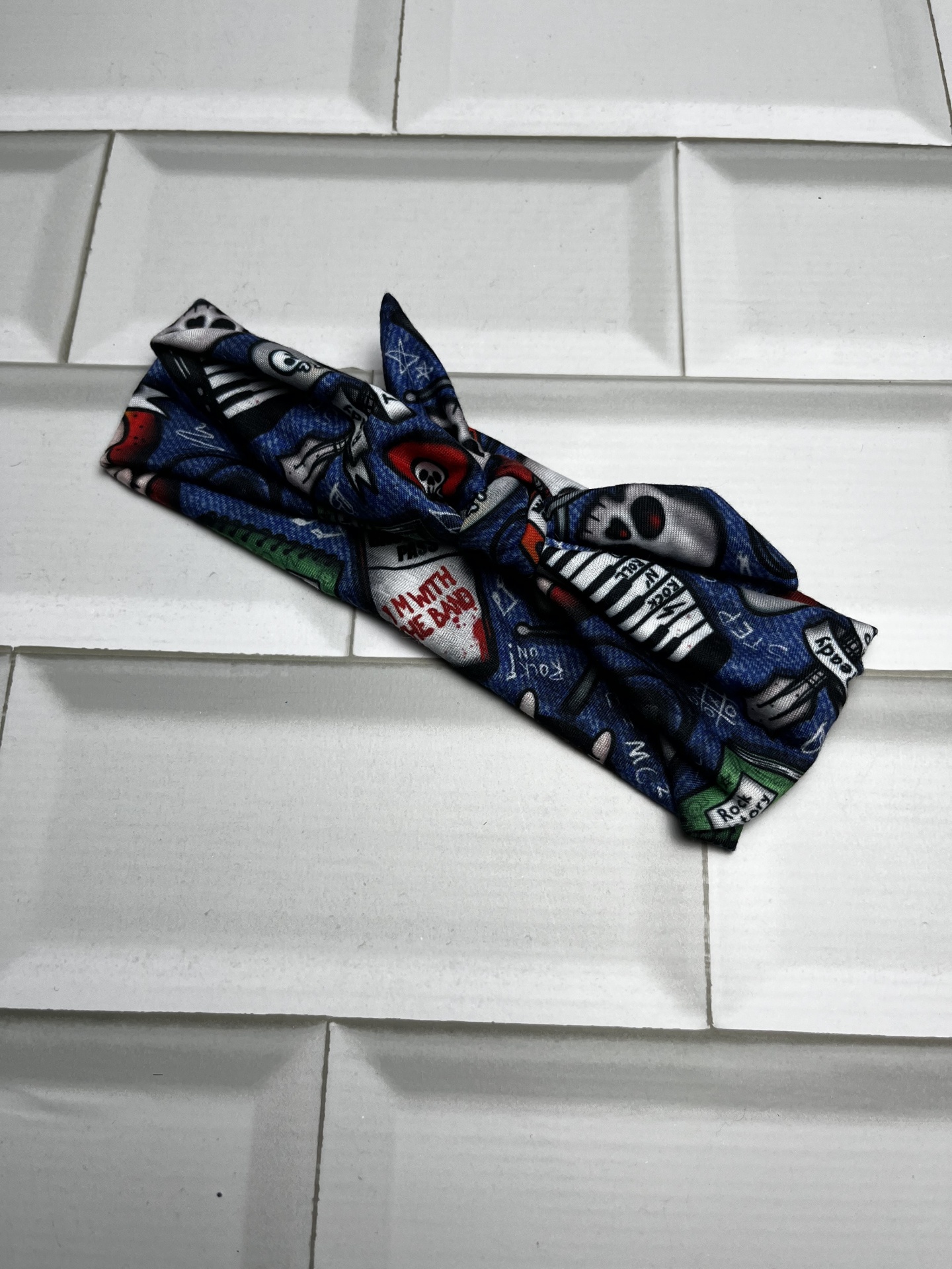 faixa de tecido preto com caveiras coloridas sobre azulejos brancos