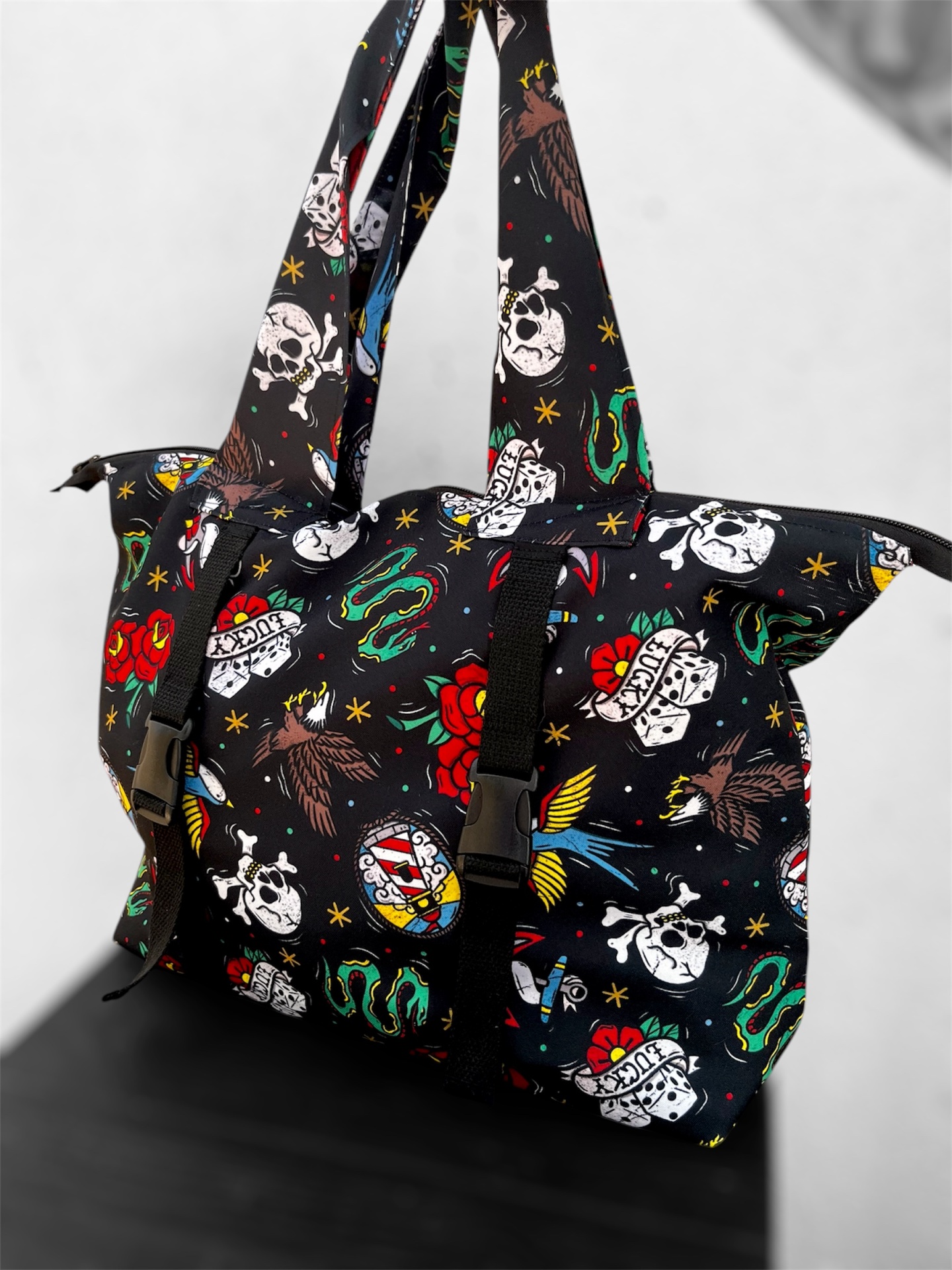 Mala de ombro preta com estampado colorido de caveiras, corações, águias e cobras