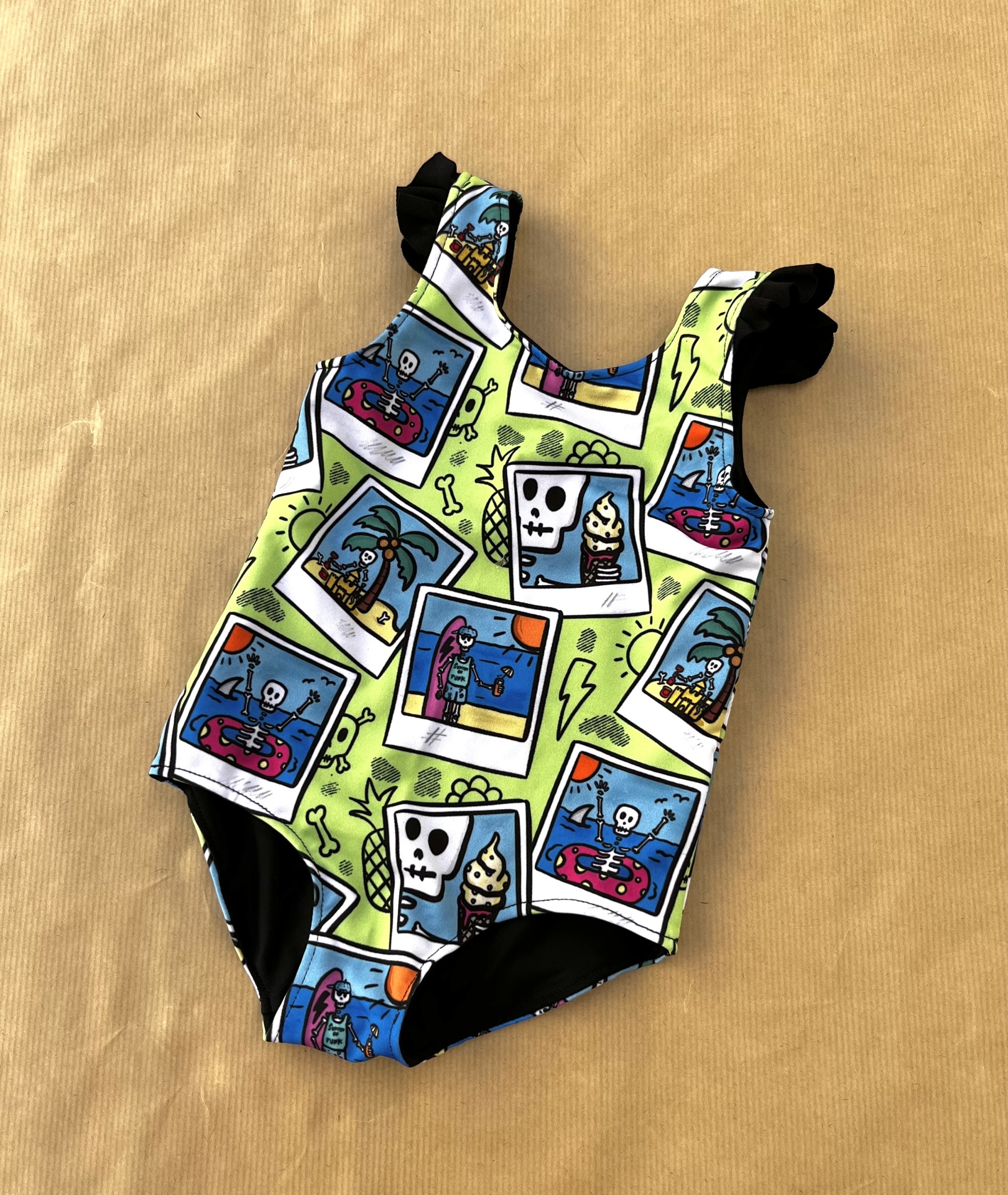 Fato de banho infantil colorido com padrões de esqueletos e palmeiras