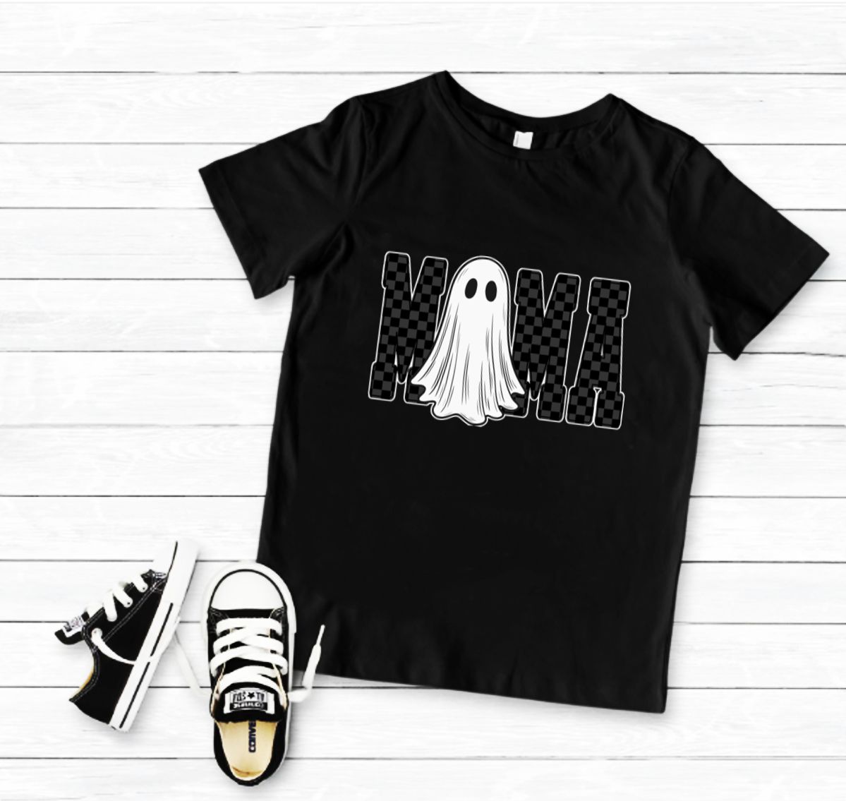 T-shirt preta com estampa de fantasma e letras M e M, com sapatilhas infantis pretas e brancas ao lado.