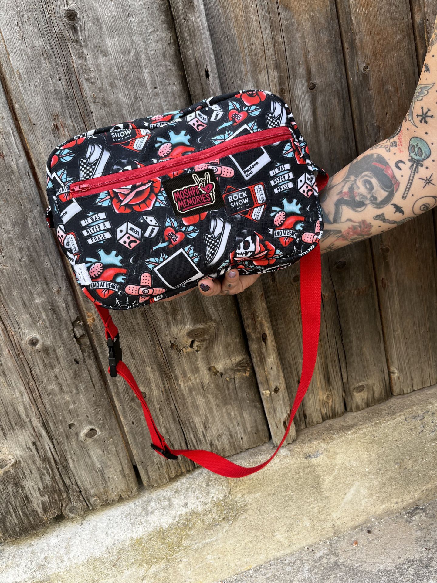 Mala tiracolo preta com padrão colorido e alça vermelha