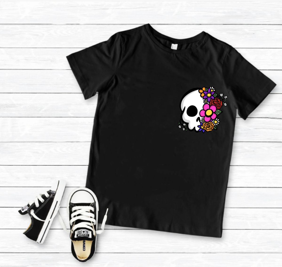 Camiseta preta com estampa de caveira e flores com sapatilhas pretas e fundo branco