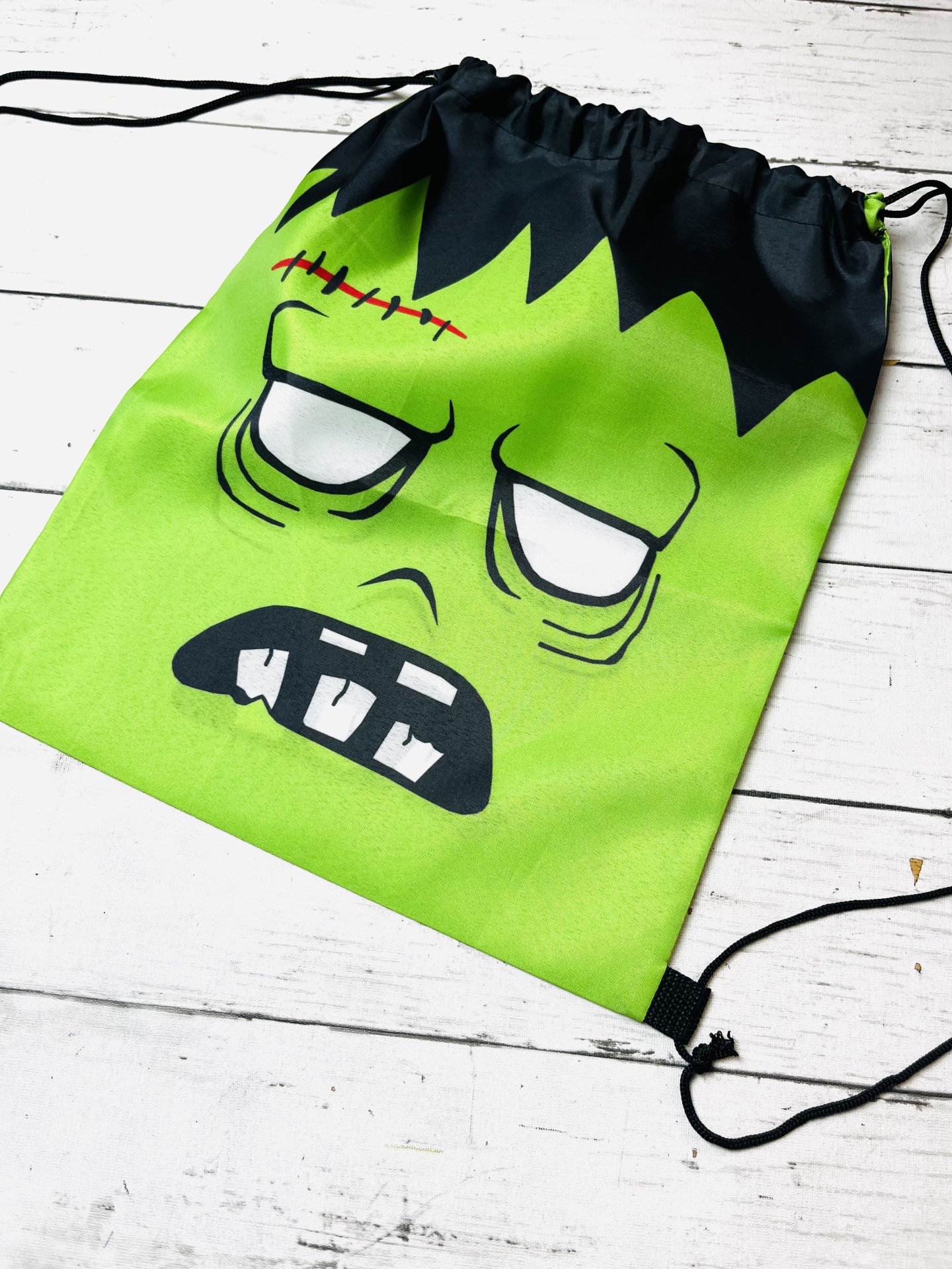 Mochila saco verde com estampa de rosto de monstro e cordões pretos