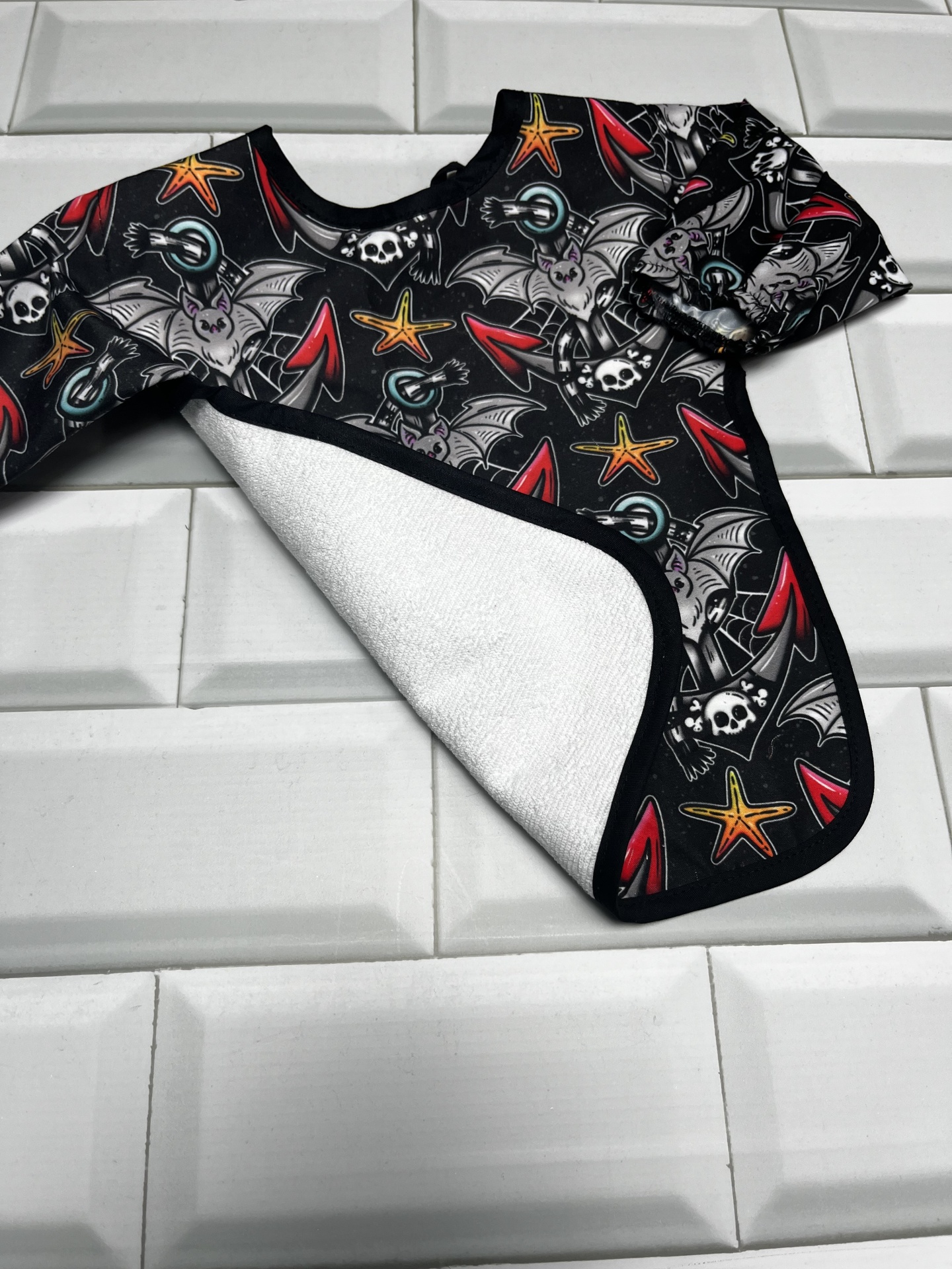 Babete de tecido preto com padrão colorido e interior branco