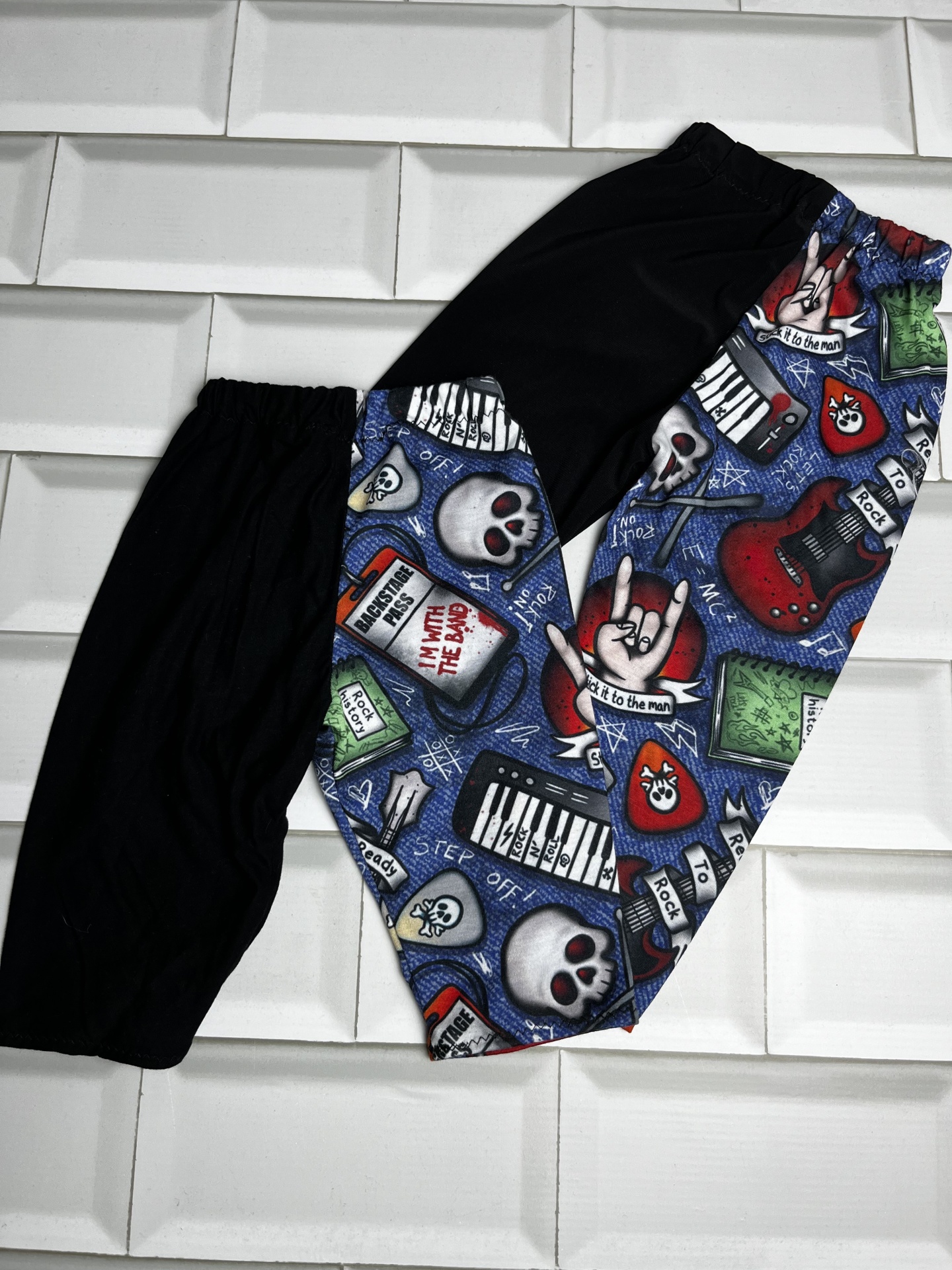 Calças compridas com padrão colorido com caveiras, guitarras, pianos e textos