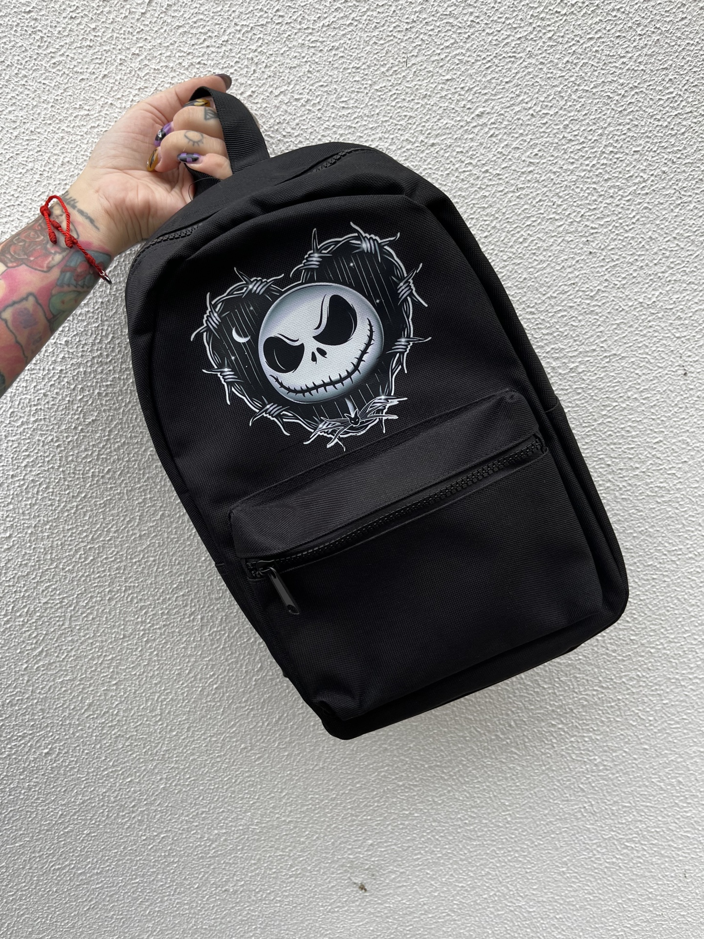 Mochila preta com desenho de caveira em arame farpado em destaque