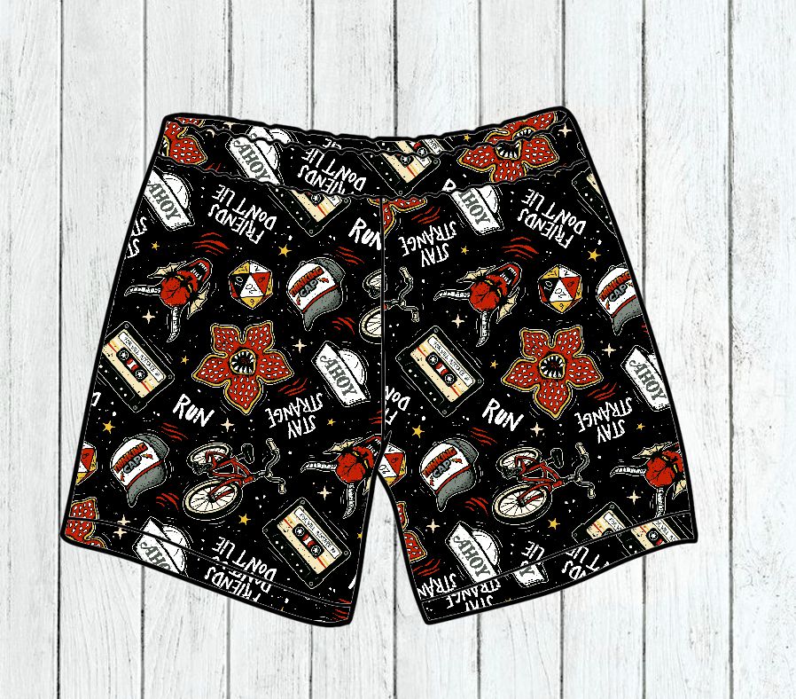 Calções pretos com padrão colorido e texto em inglês sobre fundo de madeira clara