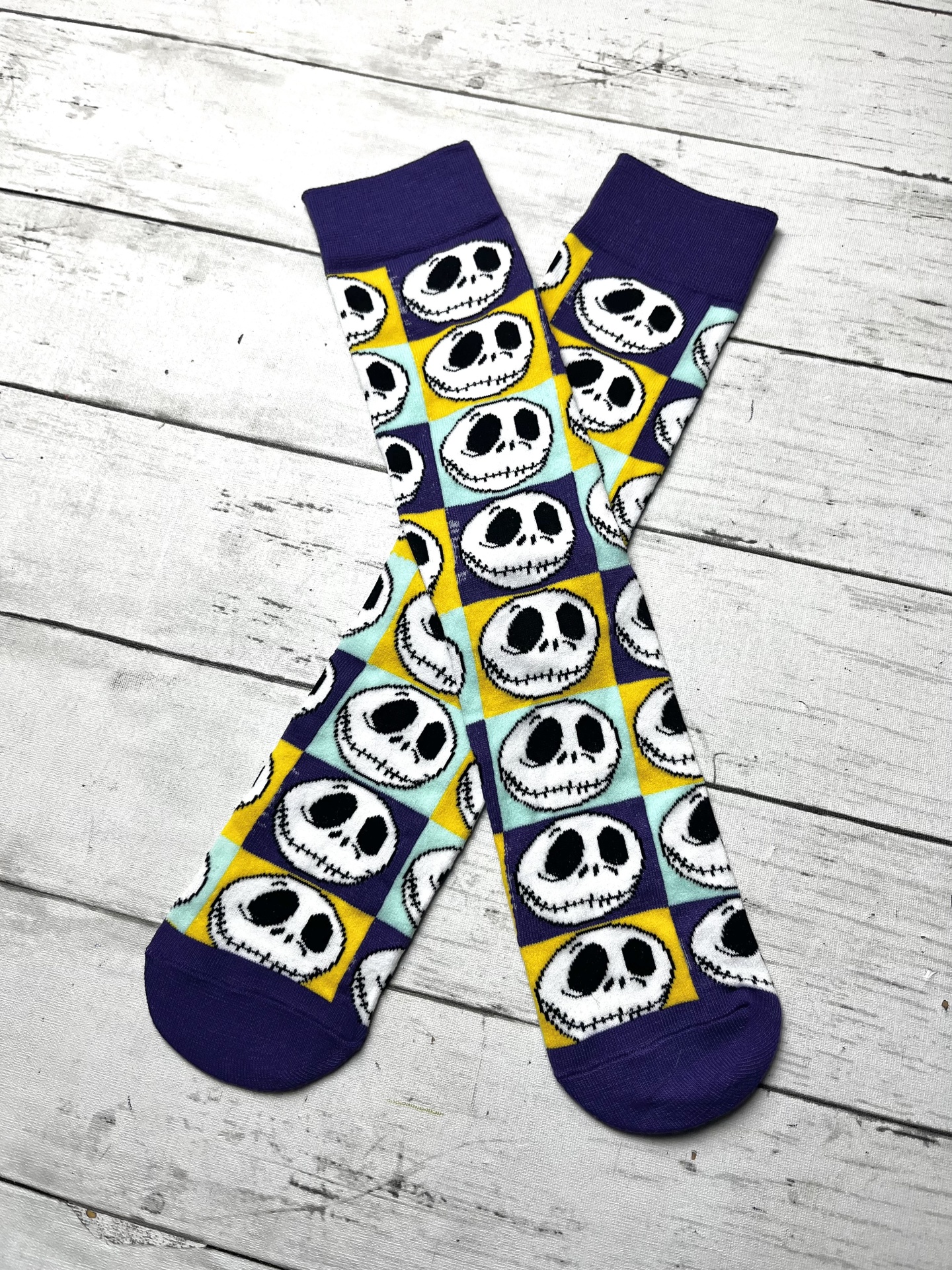 Meias compridas coloridas com padrão de caras de caveira em fundo xadrez colorido.