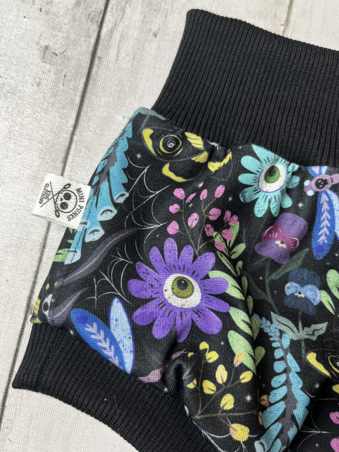 Roupas com tecido preto estampado colorido com punho preto e etiqueta branca
