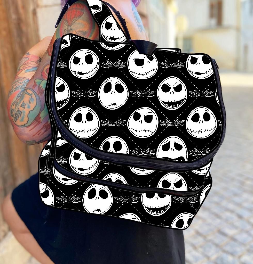 Mochila preta com padrão de caveiras brancas e expressões diferentes usada por pessoa tatuada