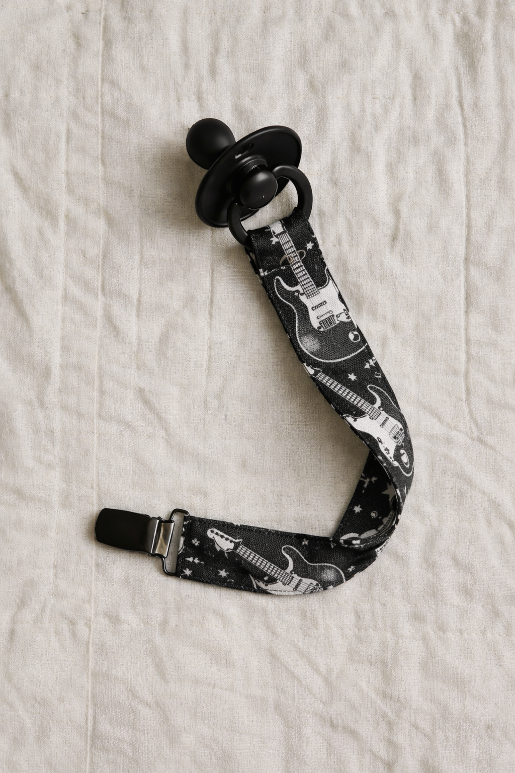Chupeta preta com suporte de tecido preto com desenhos de guitarras eléctricas