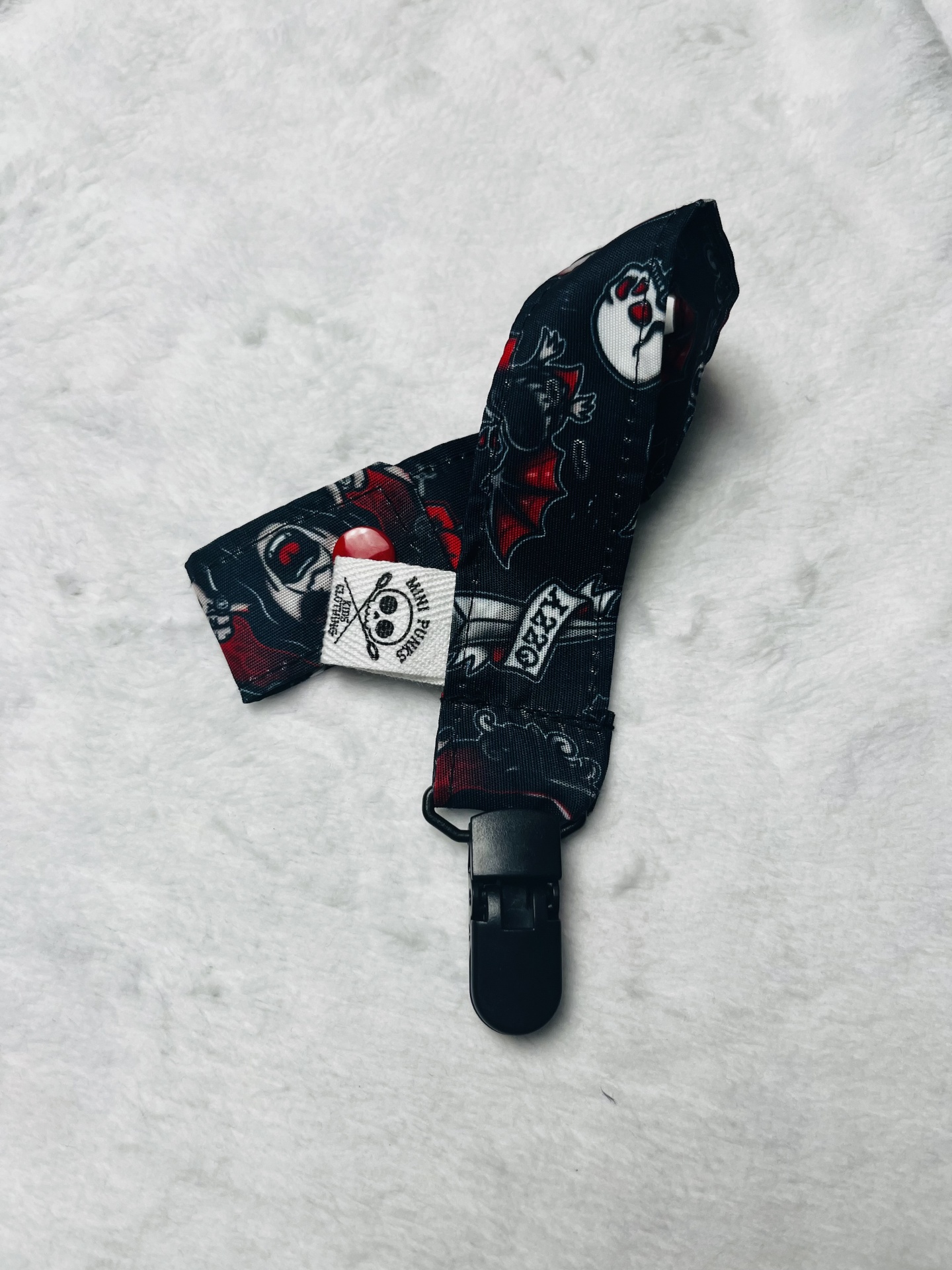 Presilha de tecido preto com estampas de morcegos e caveiras com fecho.