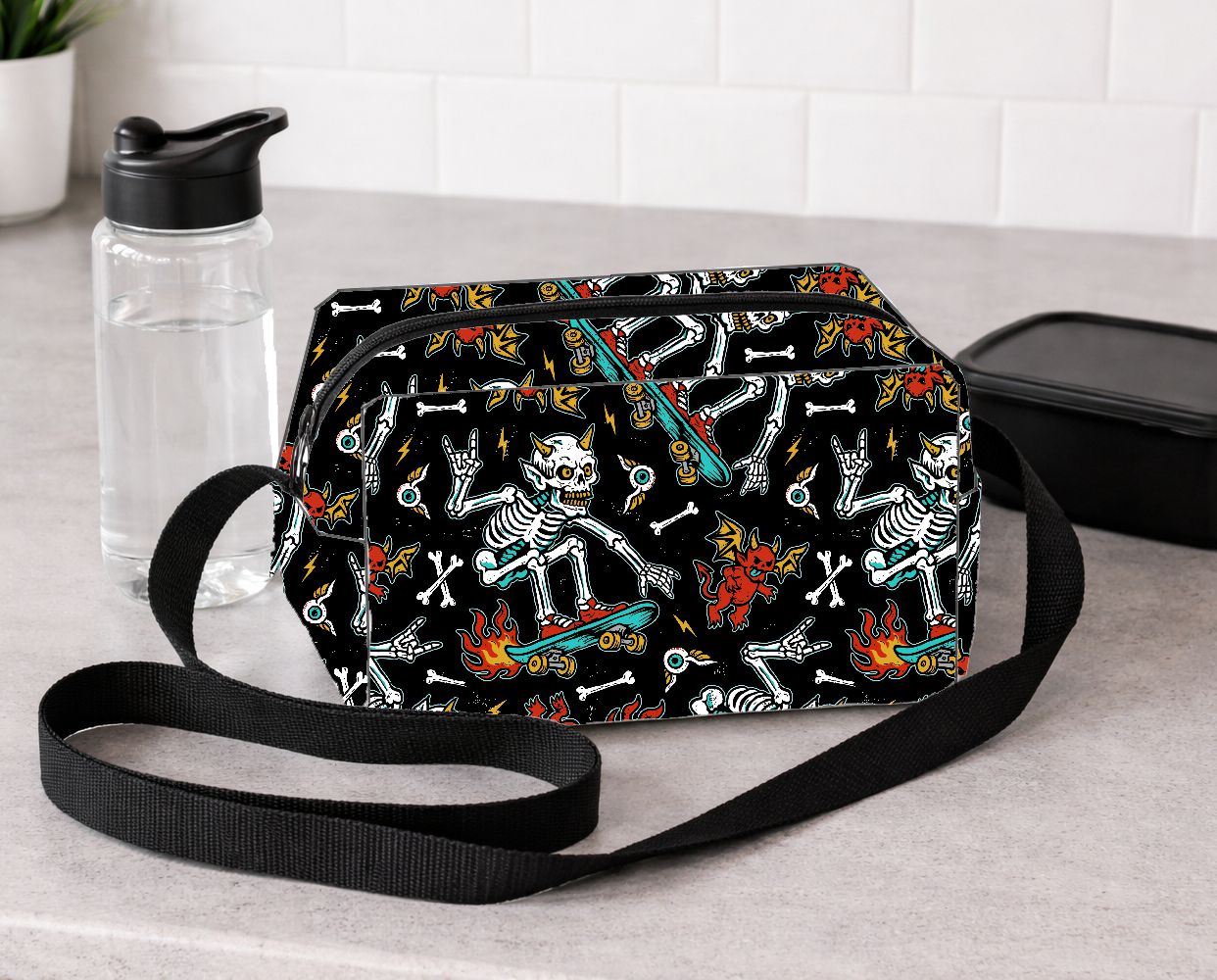 Bolsa tiracolo com padrão de esqueletos a andar de skate e diabretes vermelhos sobre fundo preto