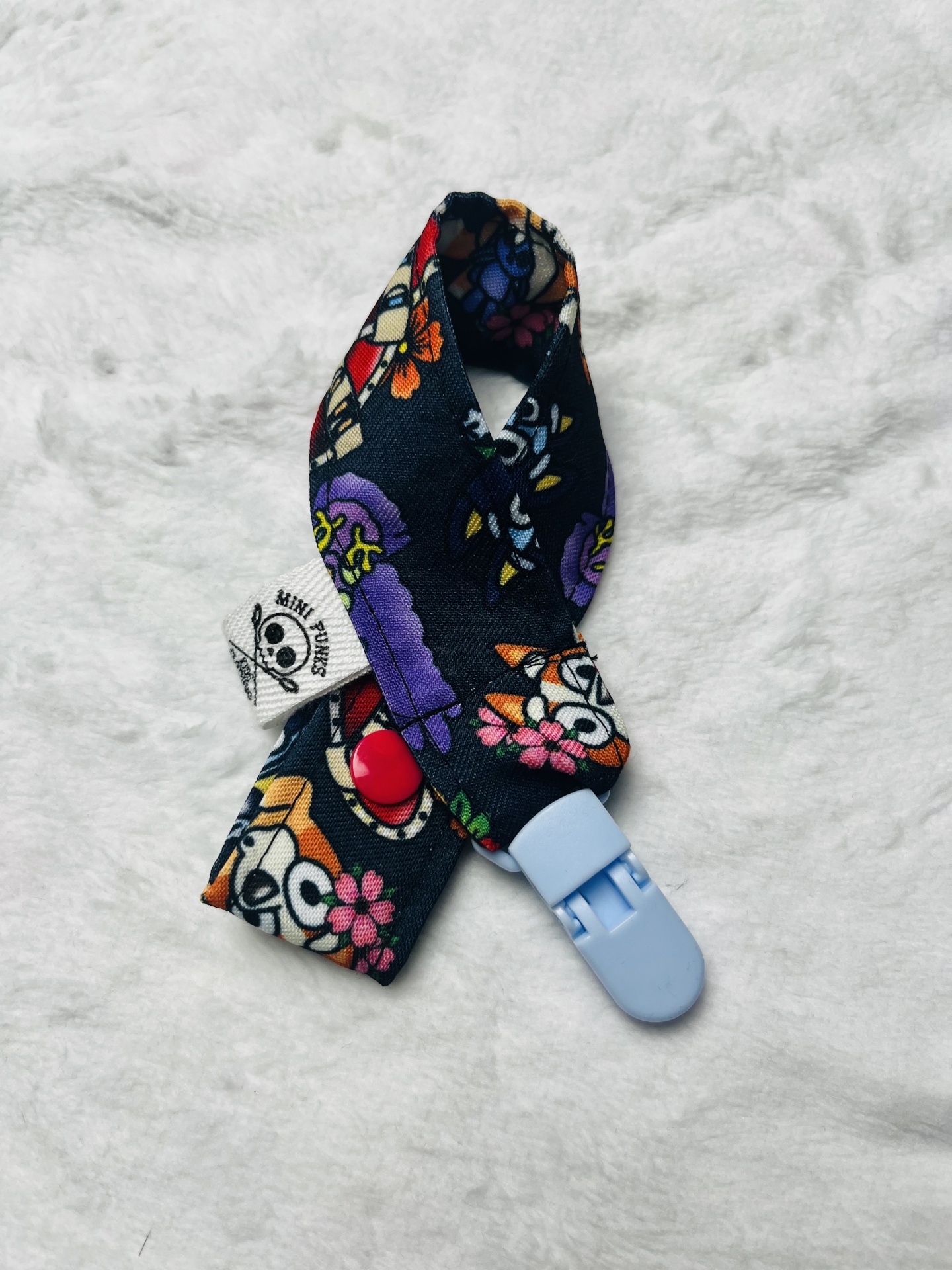 Prendedor de chupeta com padrão colorido e fecho de plástico azul