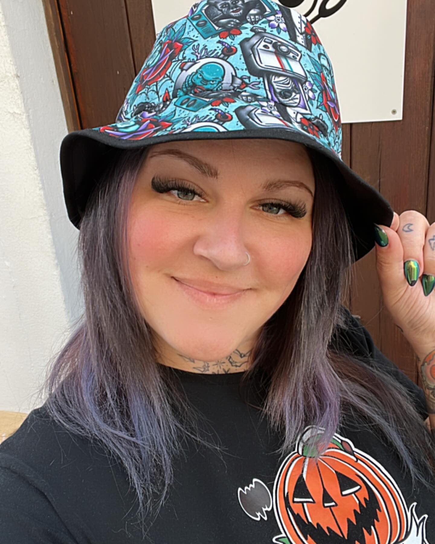 Chapéu bucket com padrão colorido e pessoa usando camisa preta com abóbora desenhada