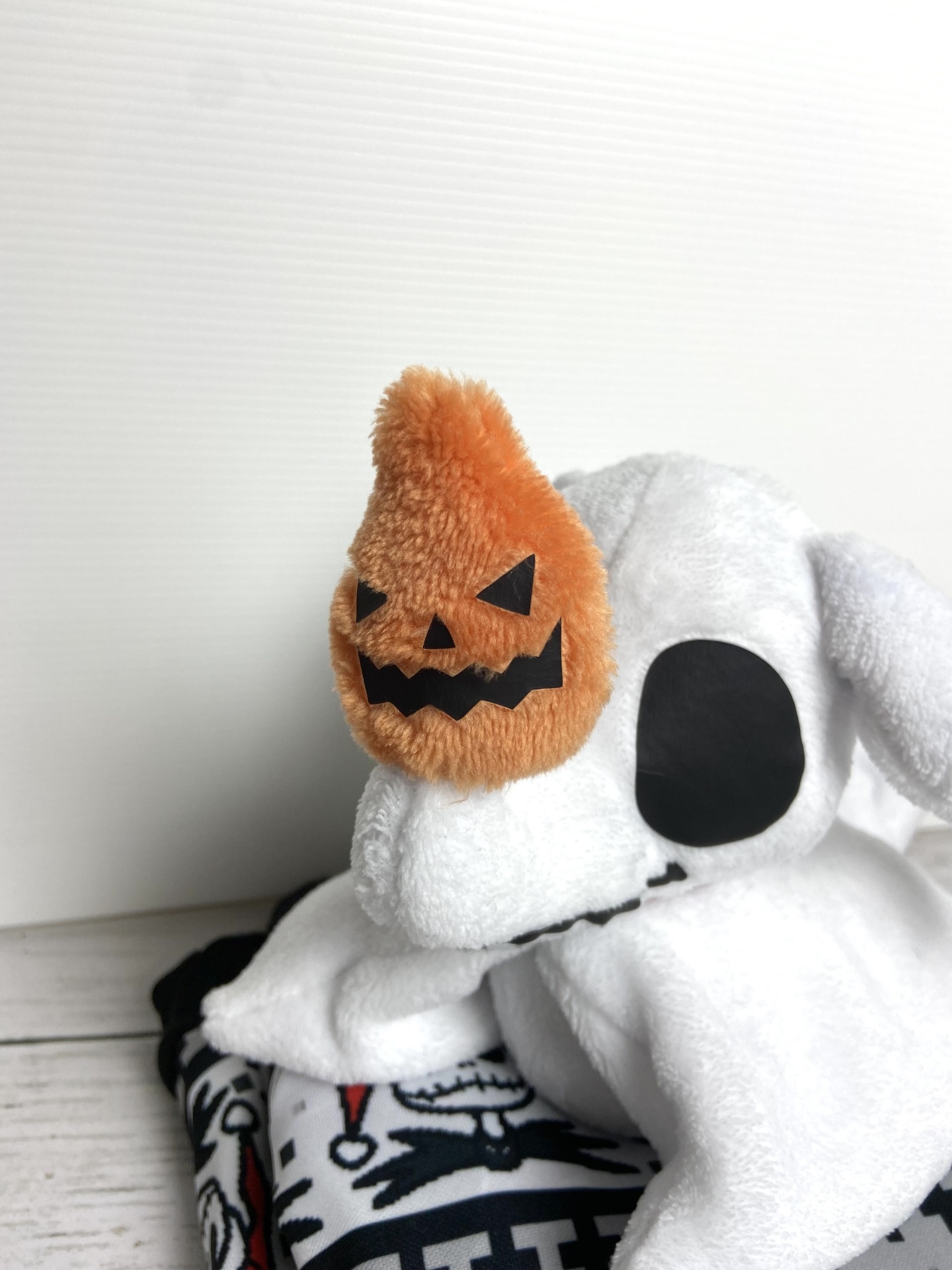 Boneco de pelúcia branco com abóbora de pelúcia laranja numa mão
