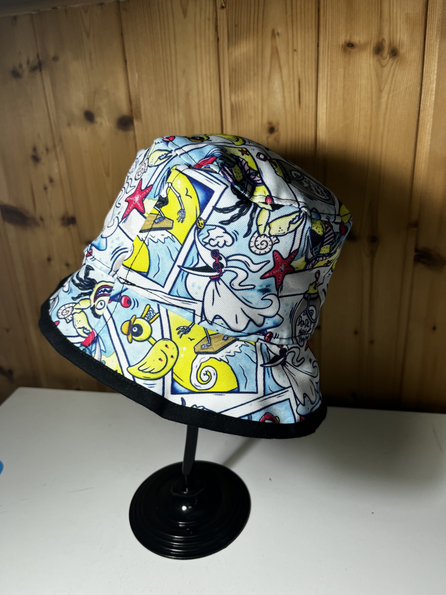 Chapéu pescador branco com padrão colorido e aba preta em suporte negro