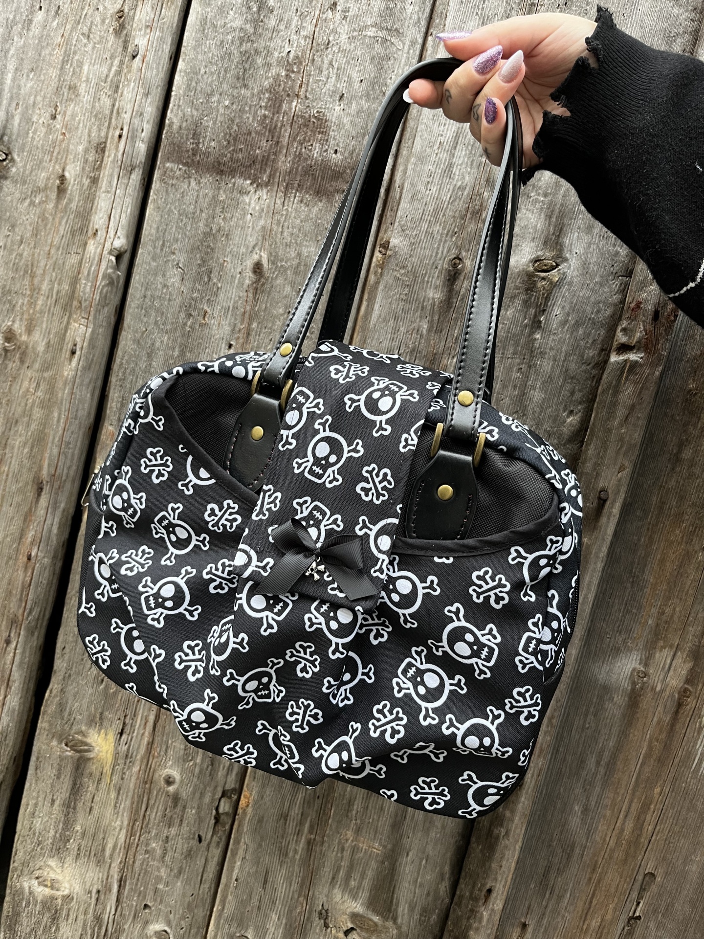 Mala preta com padrão de caveiras e alças de couro