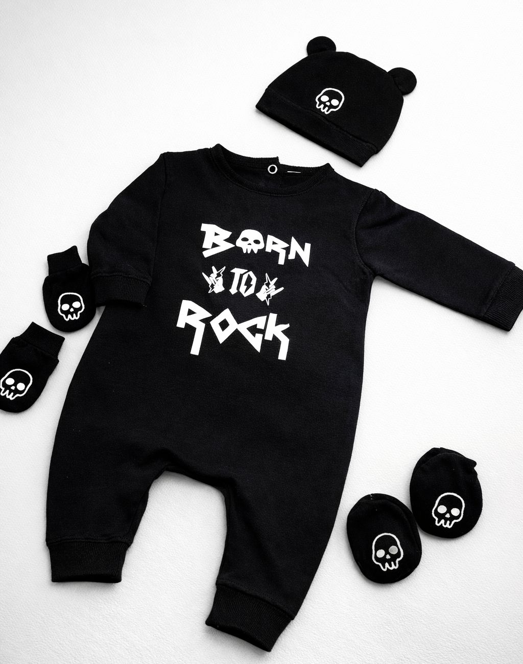 Conjunto de roupa preta de bebé com texto e símbolos brancos e acessórios com caveiras.