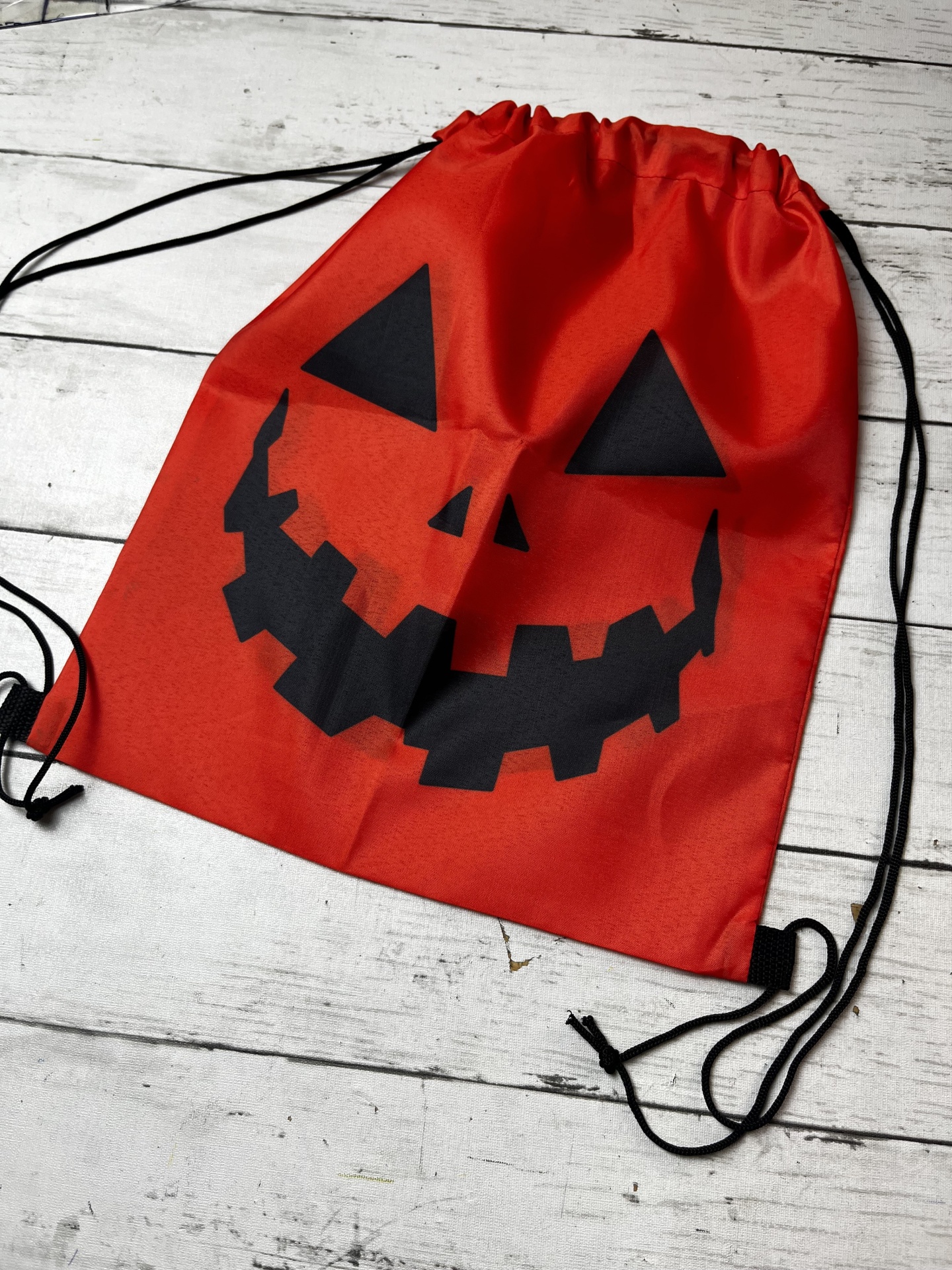 Mochila vermelha com estampa de abóbora preta e cordões pretos