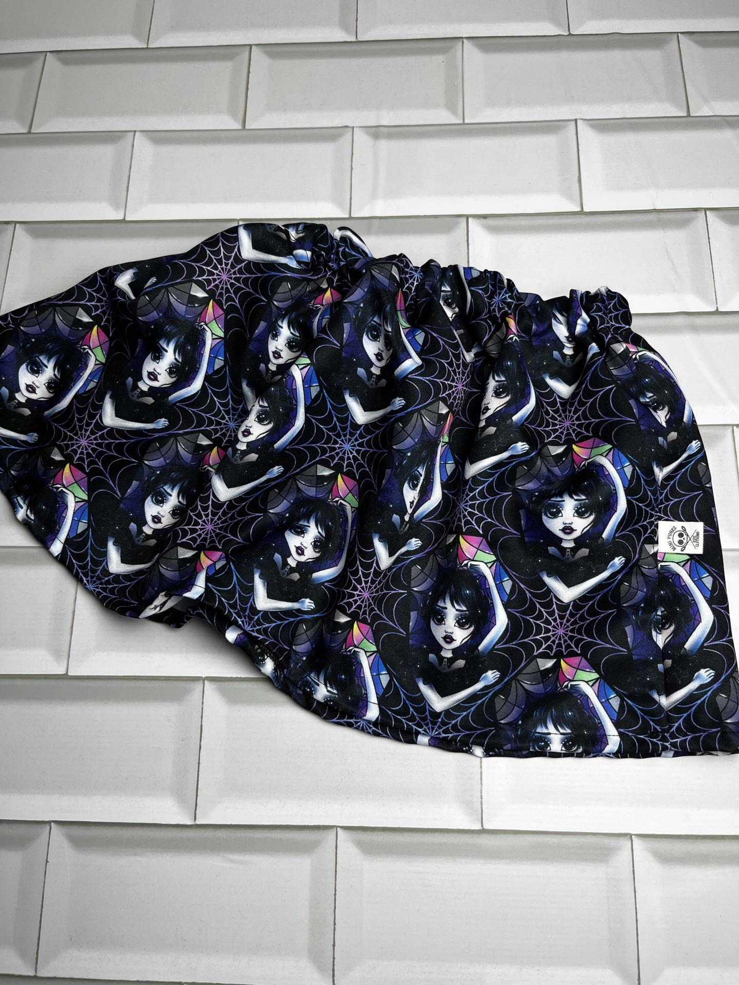 Pano com padrão repetido de personagens femininas em fundo preto com teias de aranha, tecido elástico