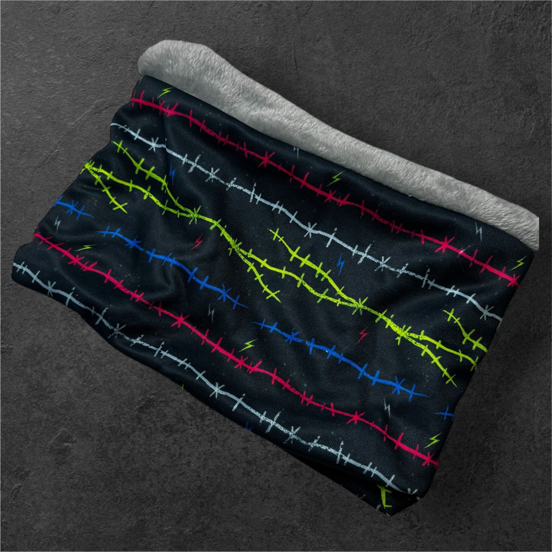Cachecol tubular preto com padrões de arame farpado coloridos e interior peludo cinza claro