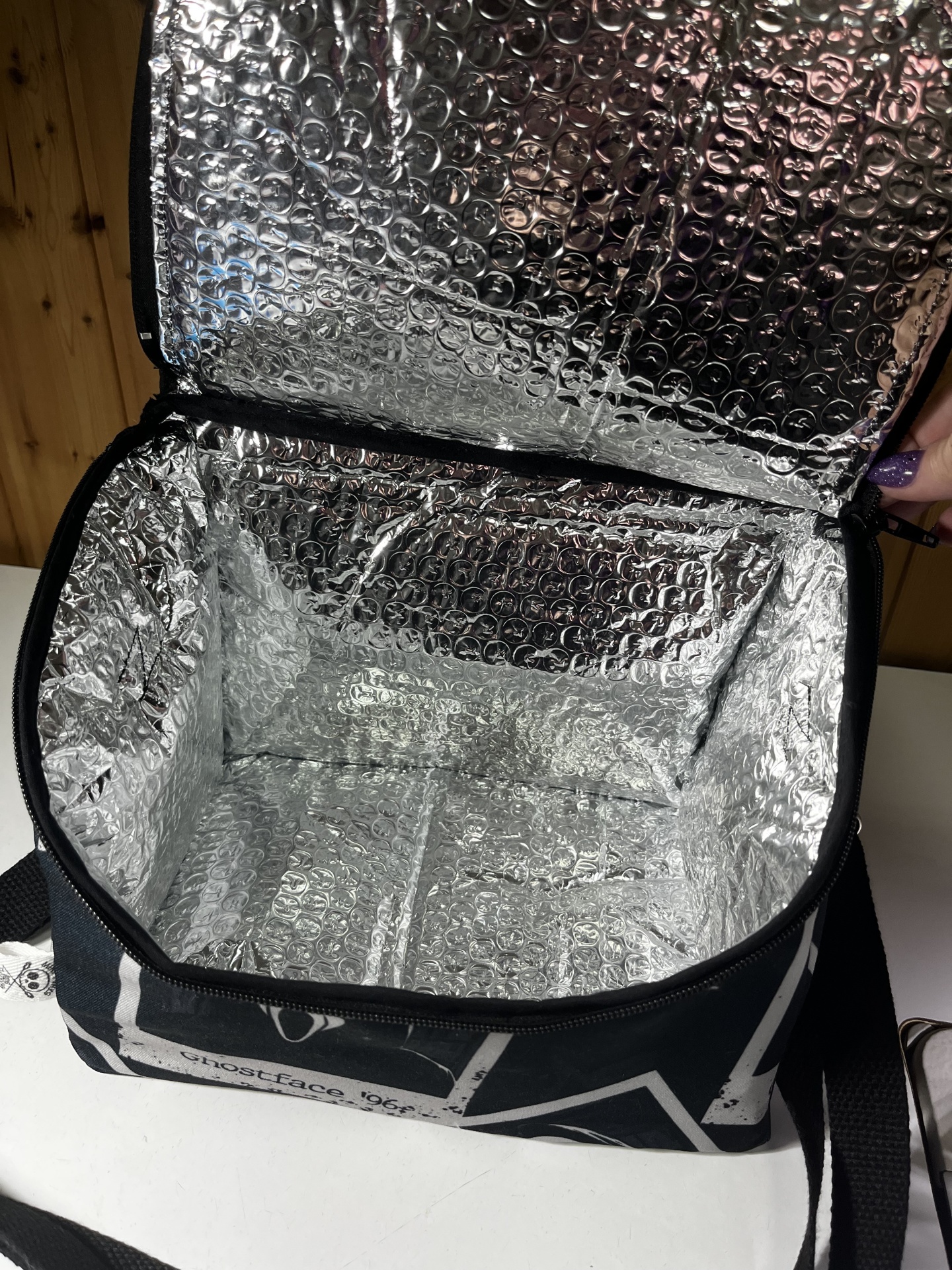 Bolsa térmica preta com interior isolante prateado e padrão em bolhas de ar
