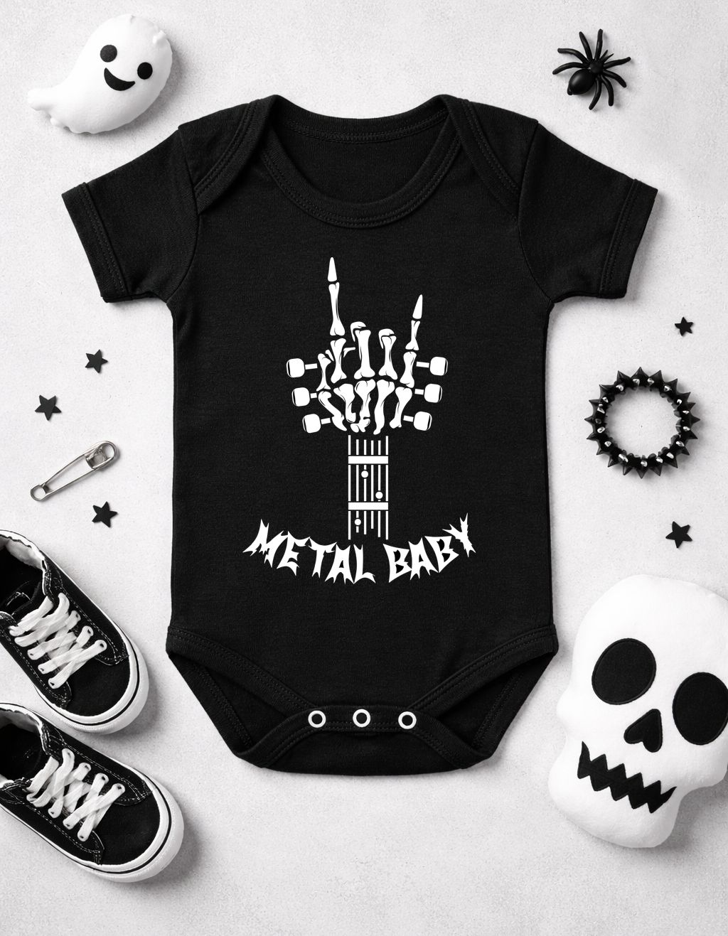 Body preto para bebé com estampa esquelética e texto METAL BABY rodeado de acessórios halloween e sapatos pretos.