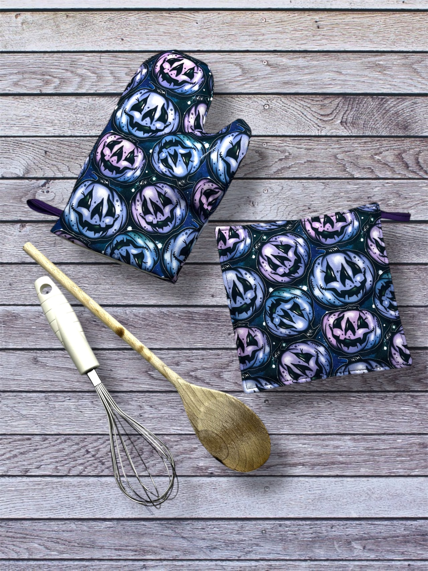 Conjunto de luva e pega-luvas de cozinha com padrão de Halloween e utensílios de cozinha sobre madeira