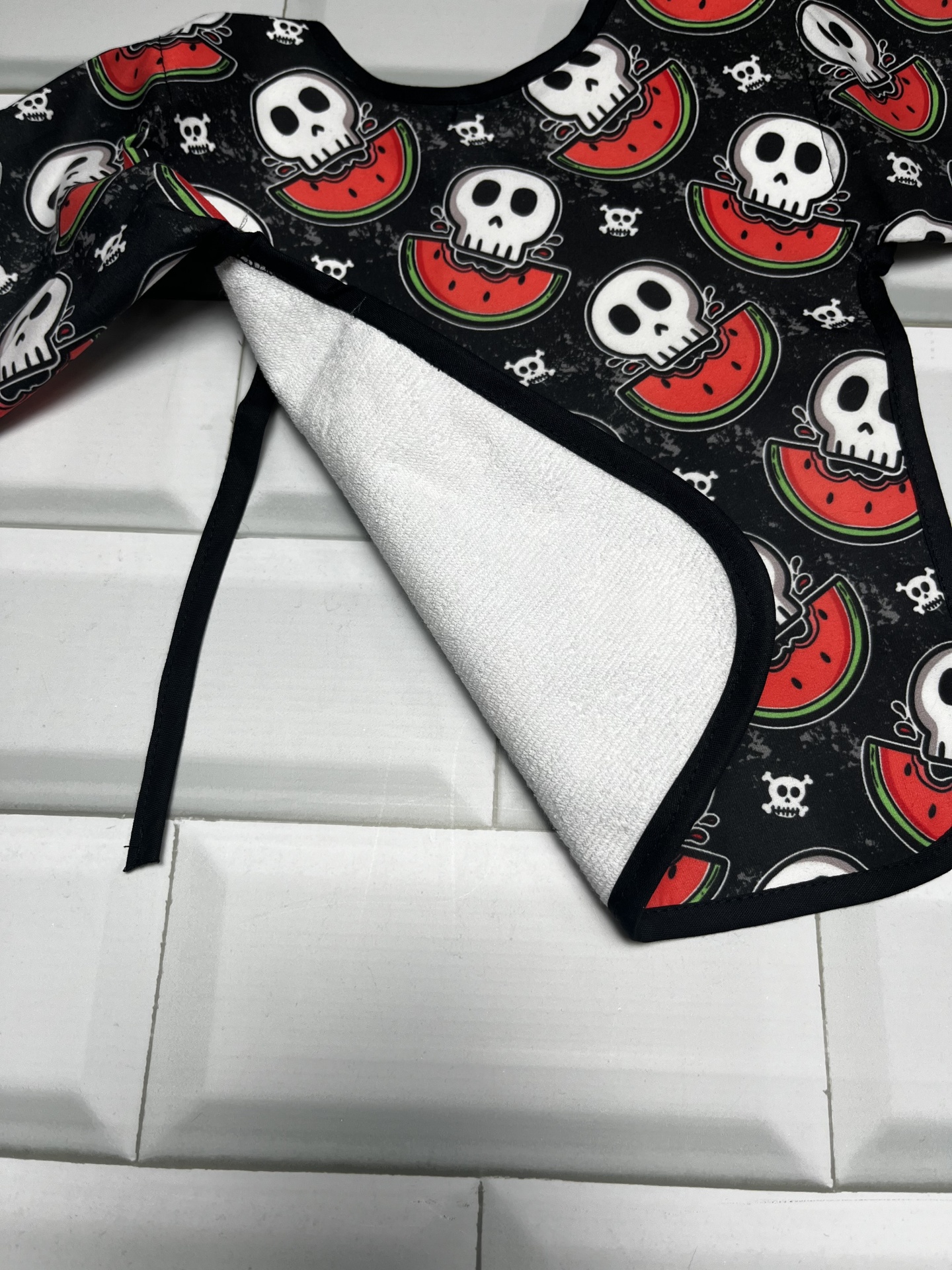 Babete para bebé com padrão de caveiras e melancia em preto