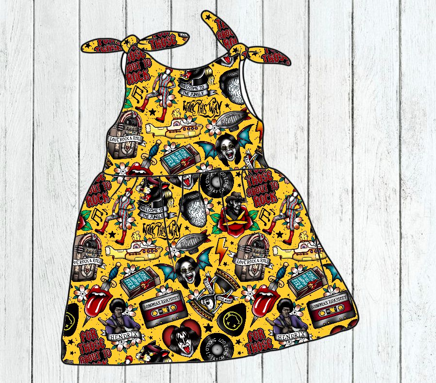 Vestido infantil colorido com padrão de desenhos e texto, sobre fundo amarelo.