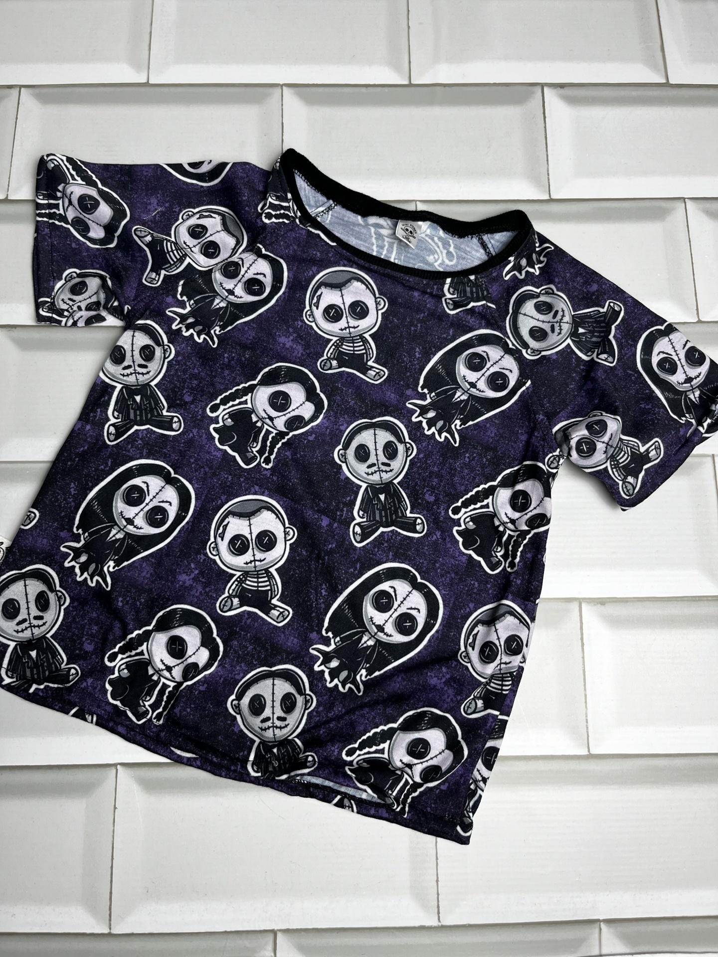 T-shirt infantil escura com padrão de personagens em fundo branco de azulejos