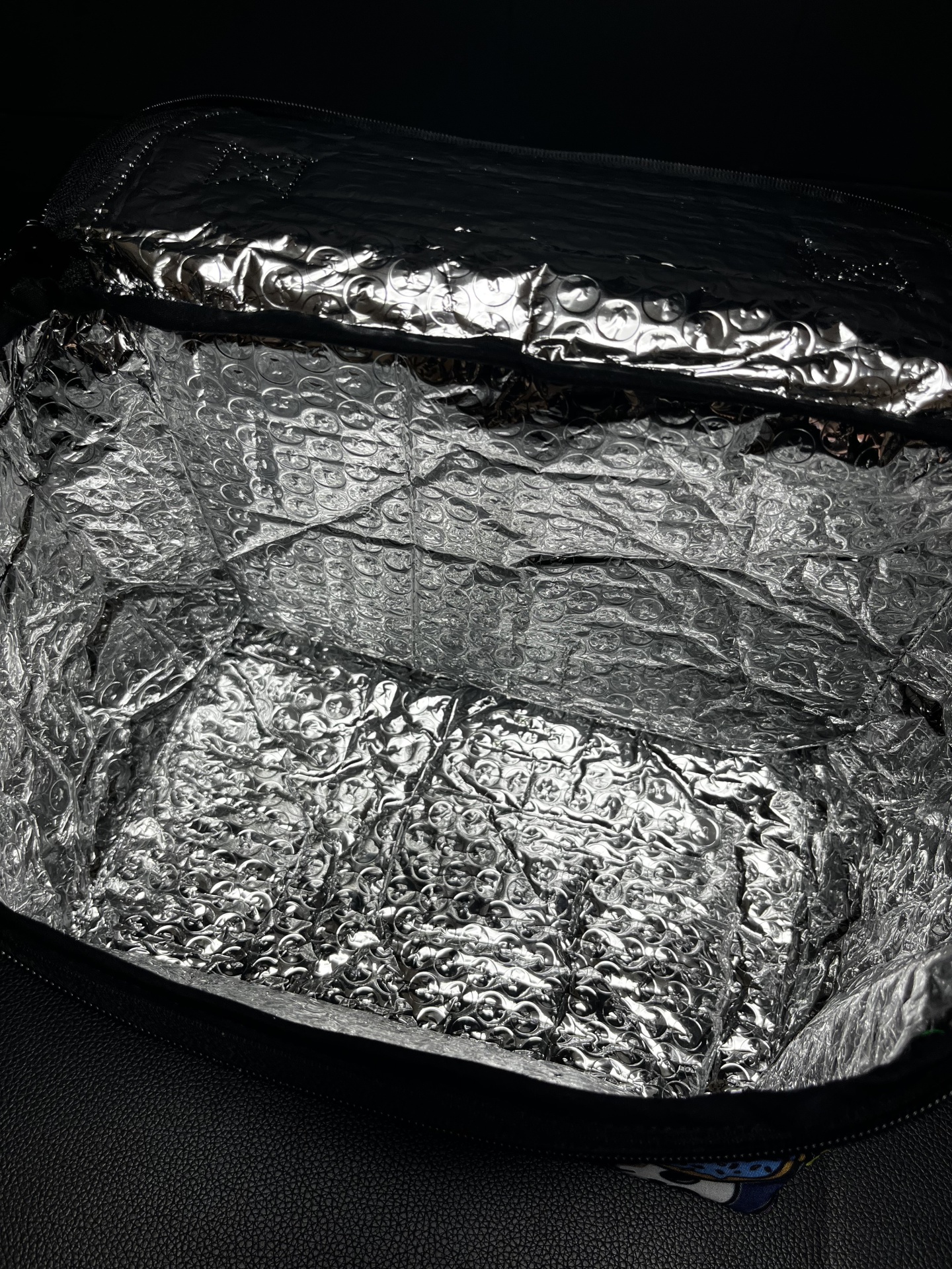 Bolsa térmica preta com interior prateado de material bolha isolante