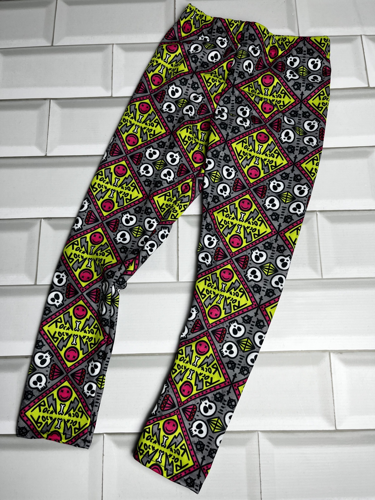 Lenço ou faixa de tecido colorida com padrão de caveiras e desenhos geométricos.