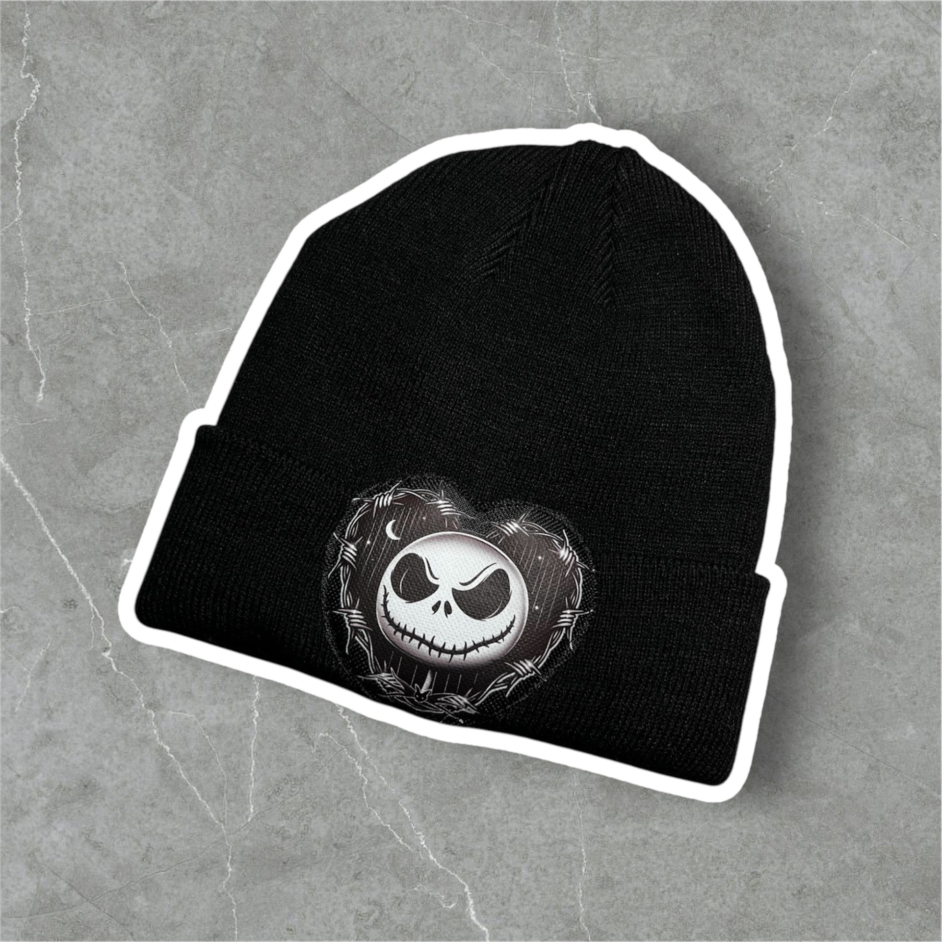 Gorro preto de malha com padrão bordado de rosto num coração cinzento sobre fundo cinzento