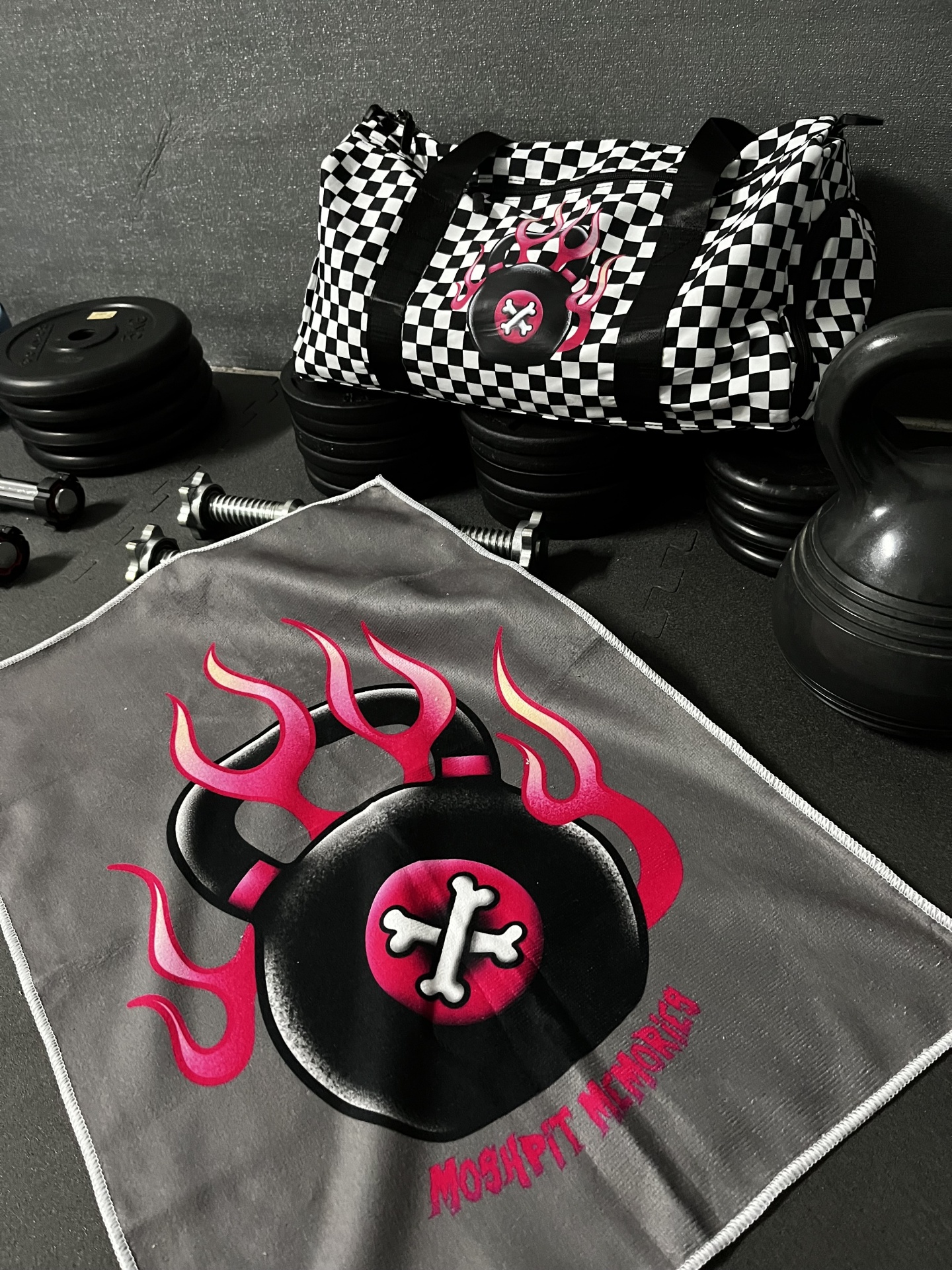 Mala desportiva xadrez preto e branco e toalha de ginásio cinzenta com gráfico kettlebell e texto MOSHPIT MEMORIA