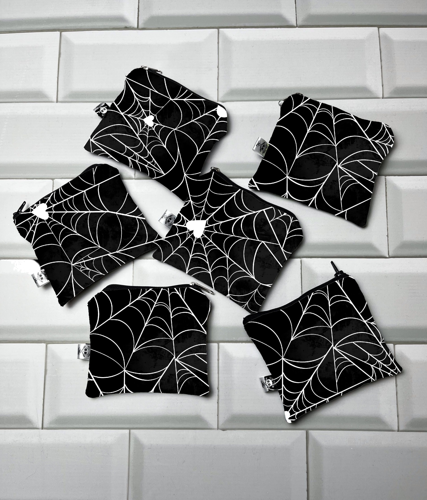 Pequenas bolsas pretas com teias de aranha brancas sobre azulejos brancos.