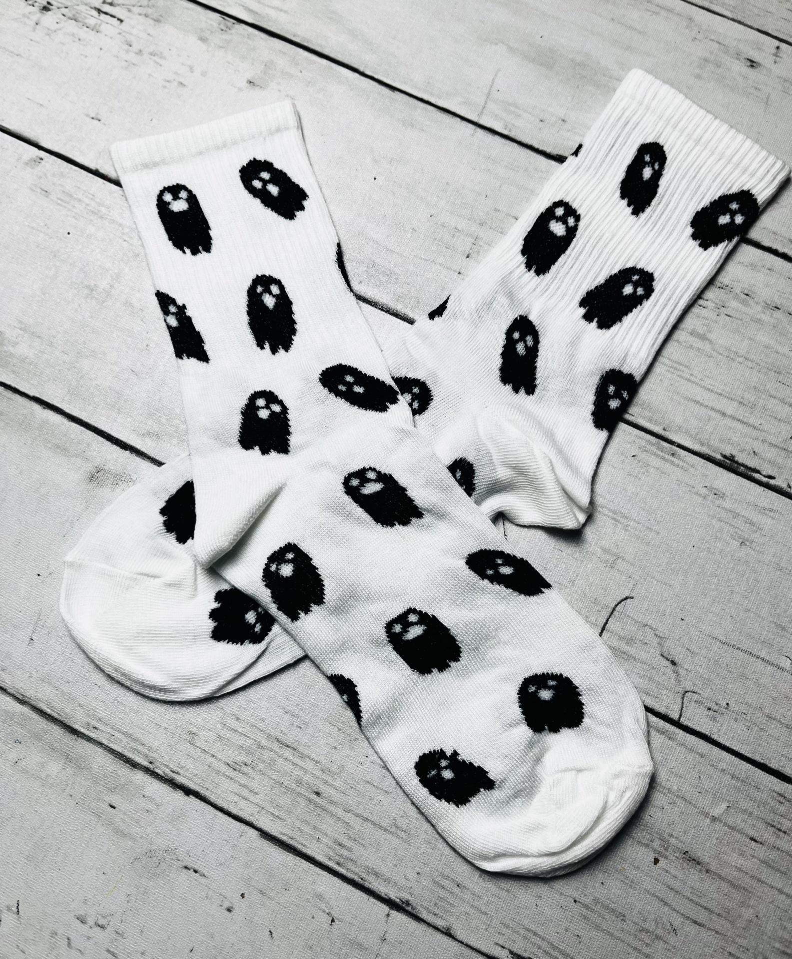 Meias brancas com padrão de fantasmas pretos sobre madeira branca