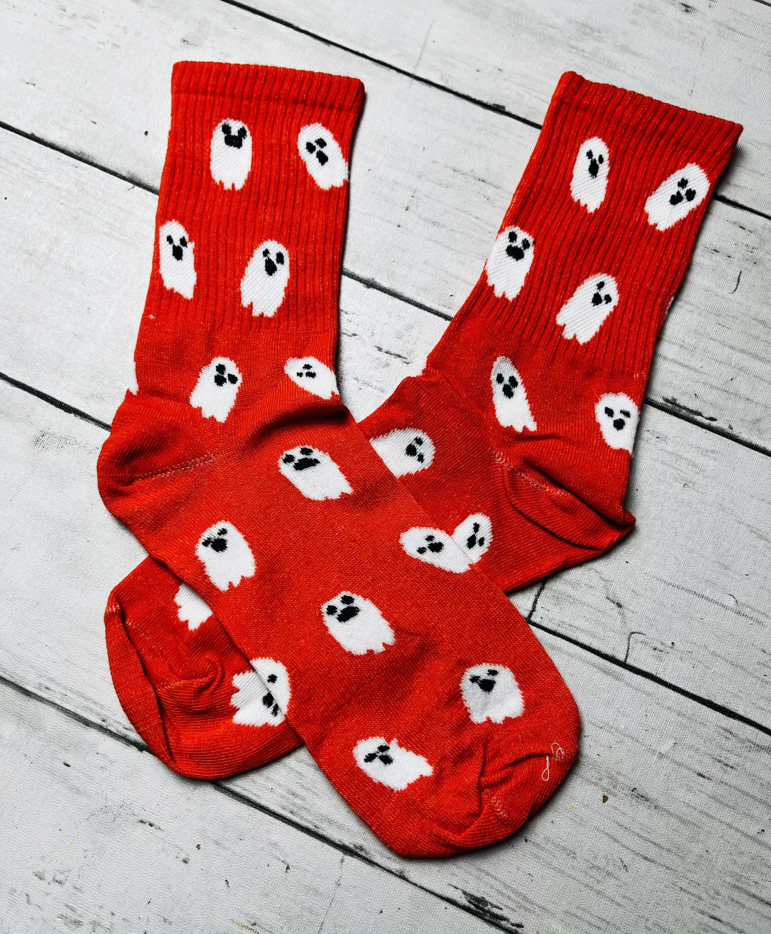 meias vermelhas com fantasmas brancos e olhos pretos sobre chão de madeira branca