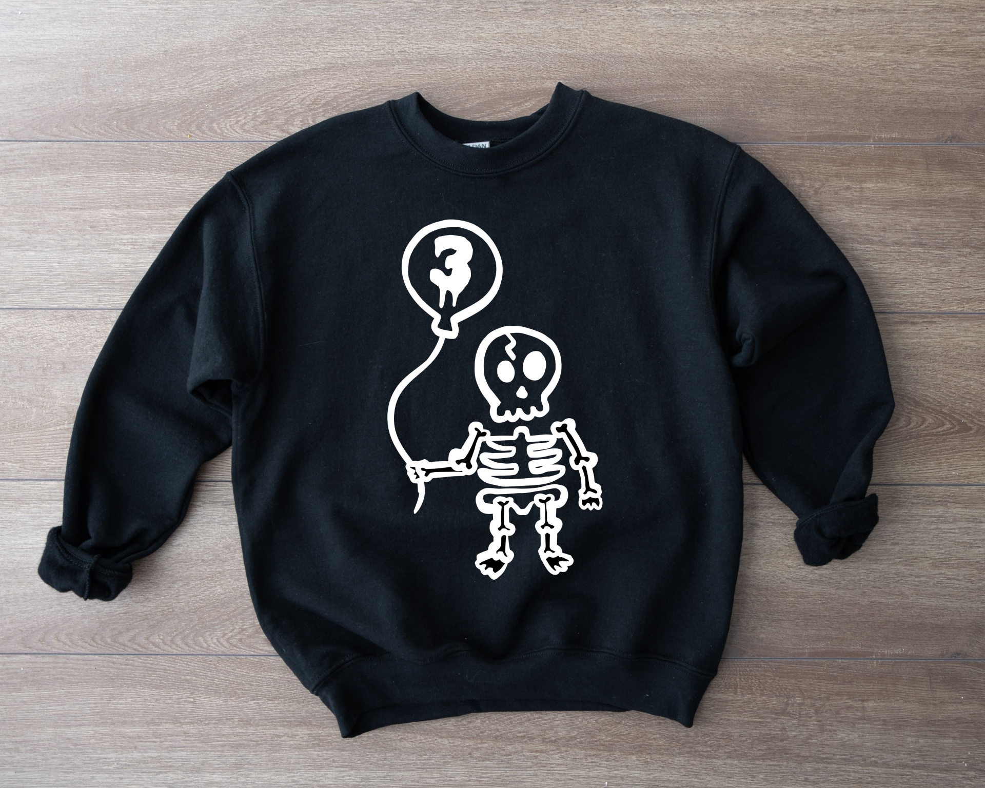Sweatshirt preta com desenho branco de esqueleto segurando balão