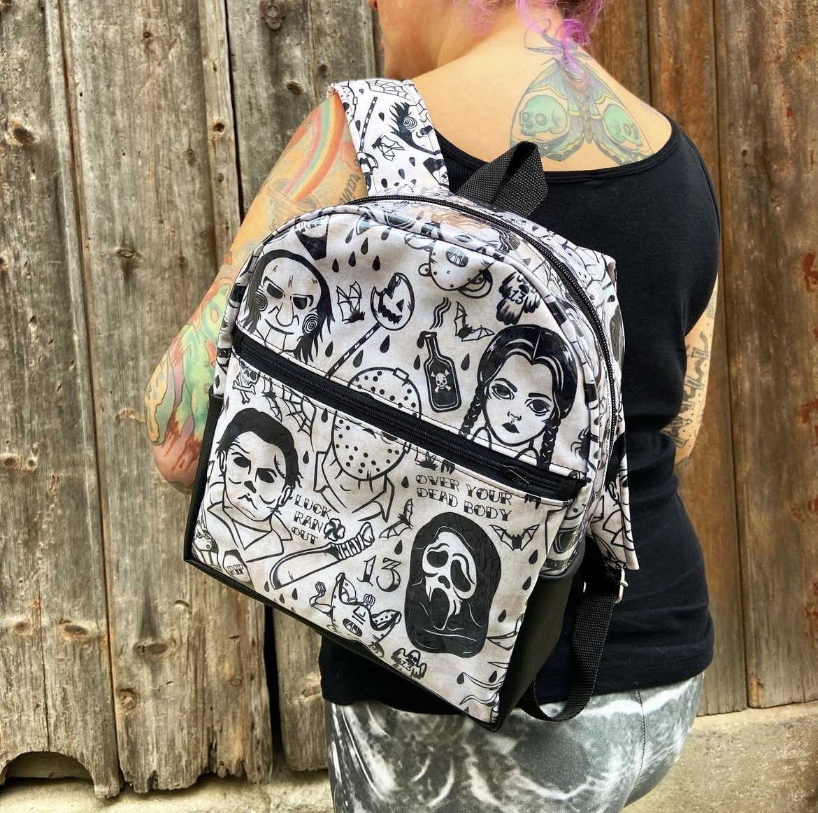 Mochila preta e branca com estampas de personagens de filmes de terror usada em pessoa