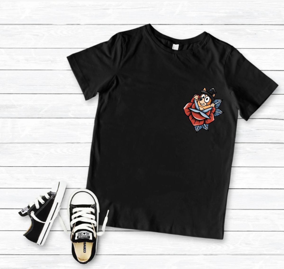 T-shirt preta com personagem de desenho animado segurando rosa e ténis pretos com atacadores brancos